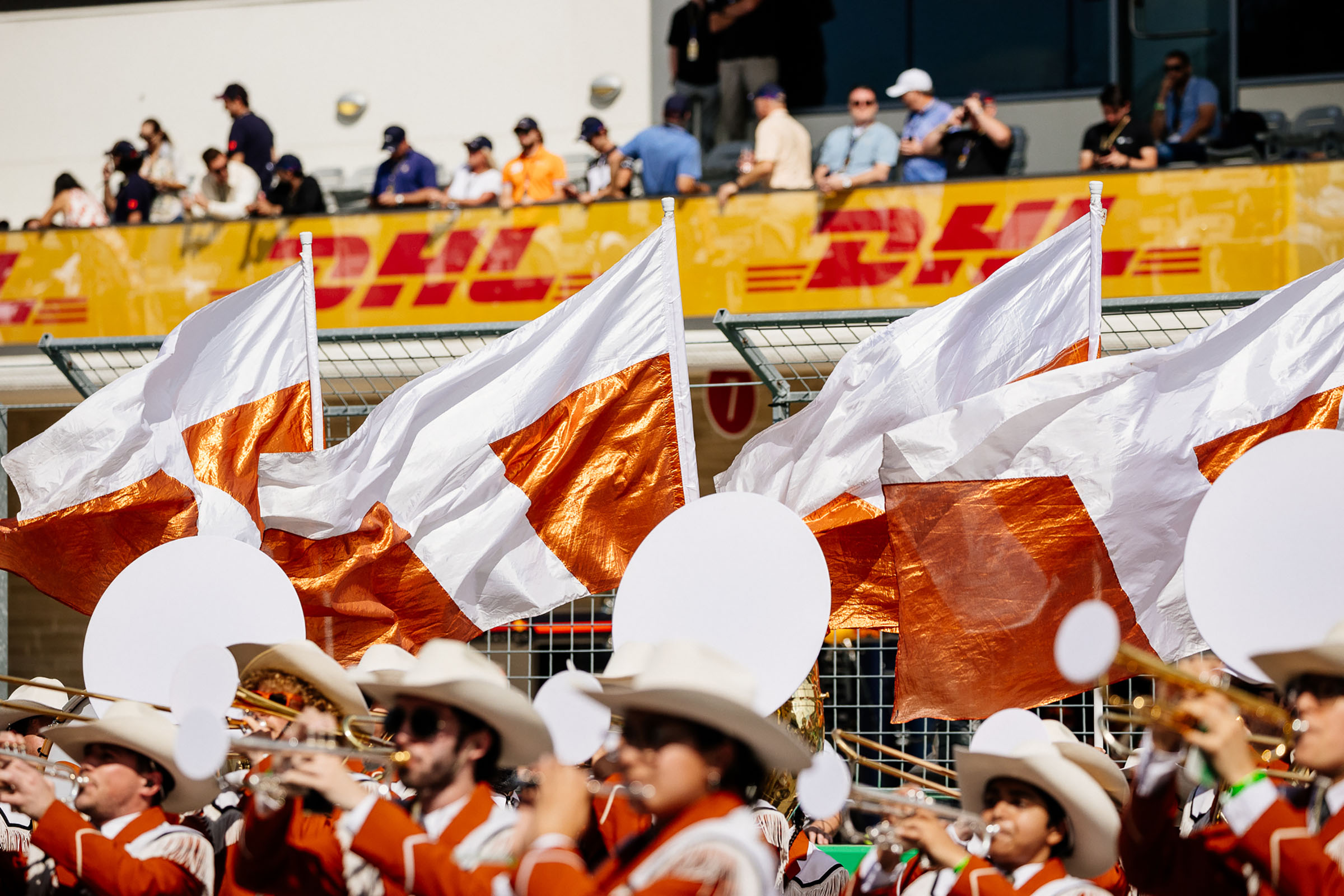 Burnt orange and white flags wave above a group of musicians wearing cowboy hats