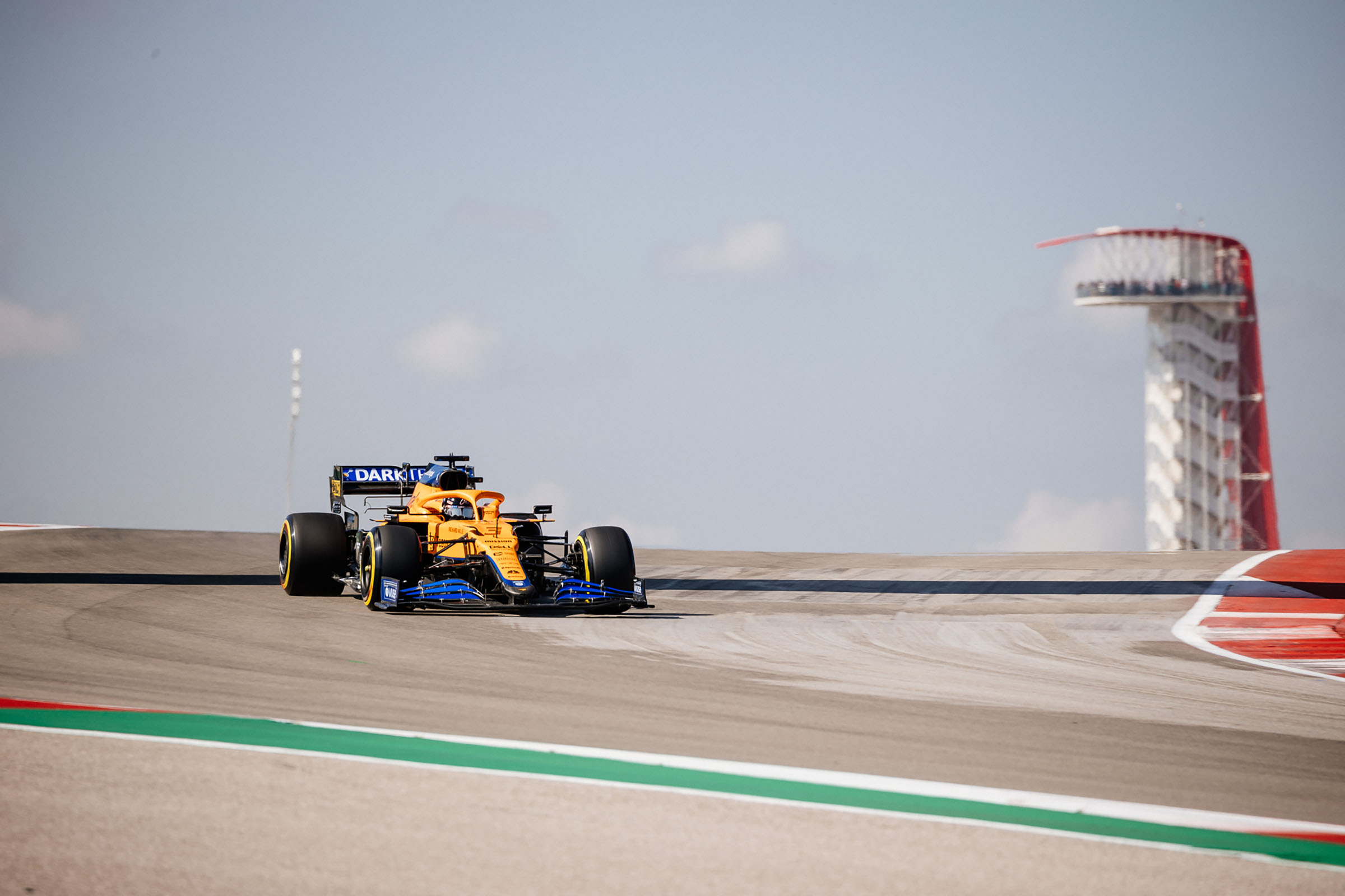 A yellow and blue car rounds a gray and green racetrack