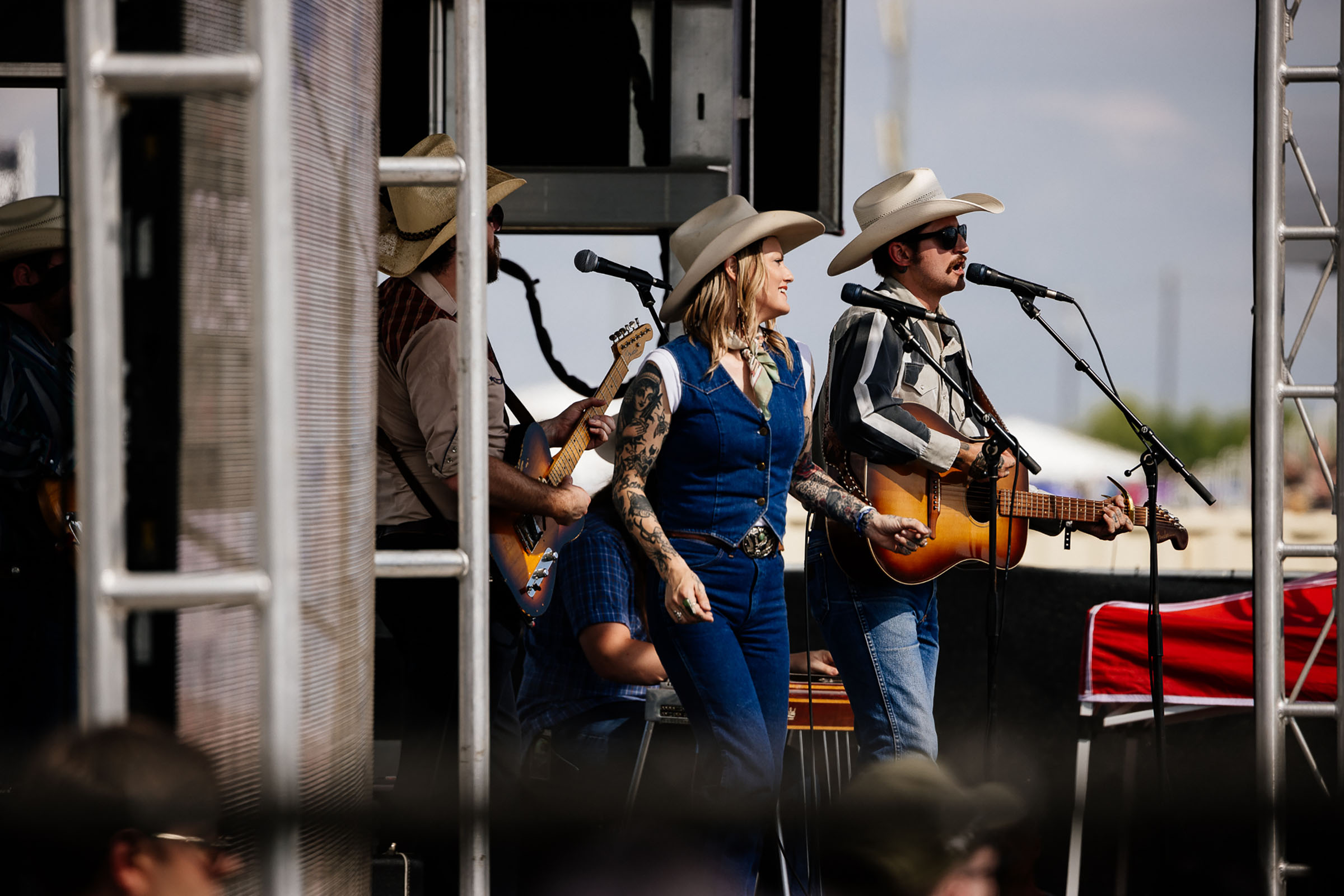A pair of singers sing into microphones on a stage.