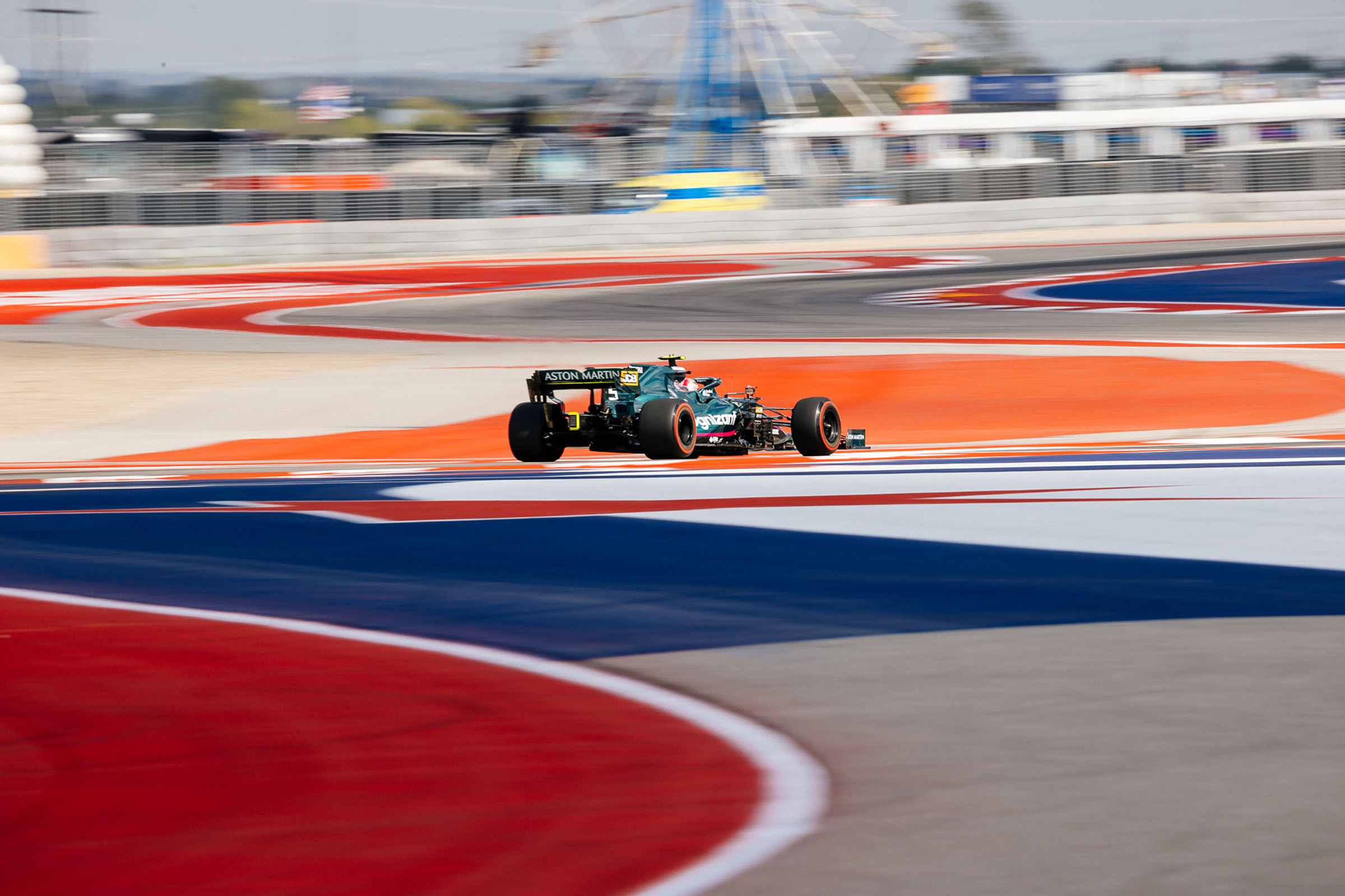 A orange and blue car drives away from the camera on a brightly-painted track