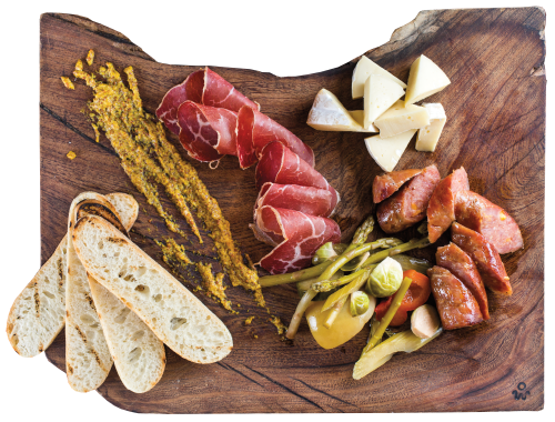 An overhead view of a wooden board topped with a selection of meats, cheeses and bread