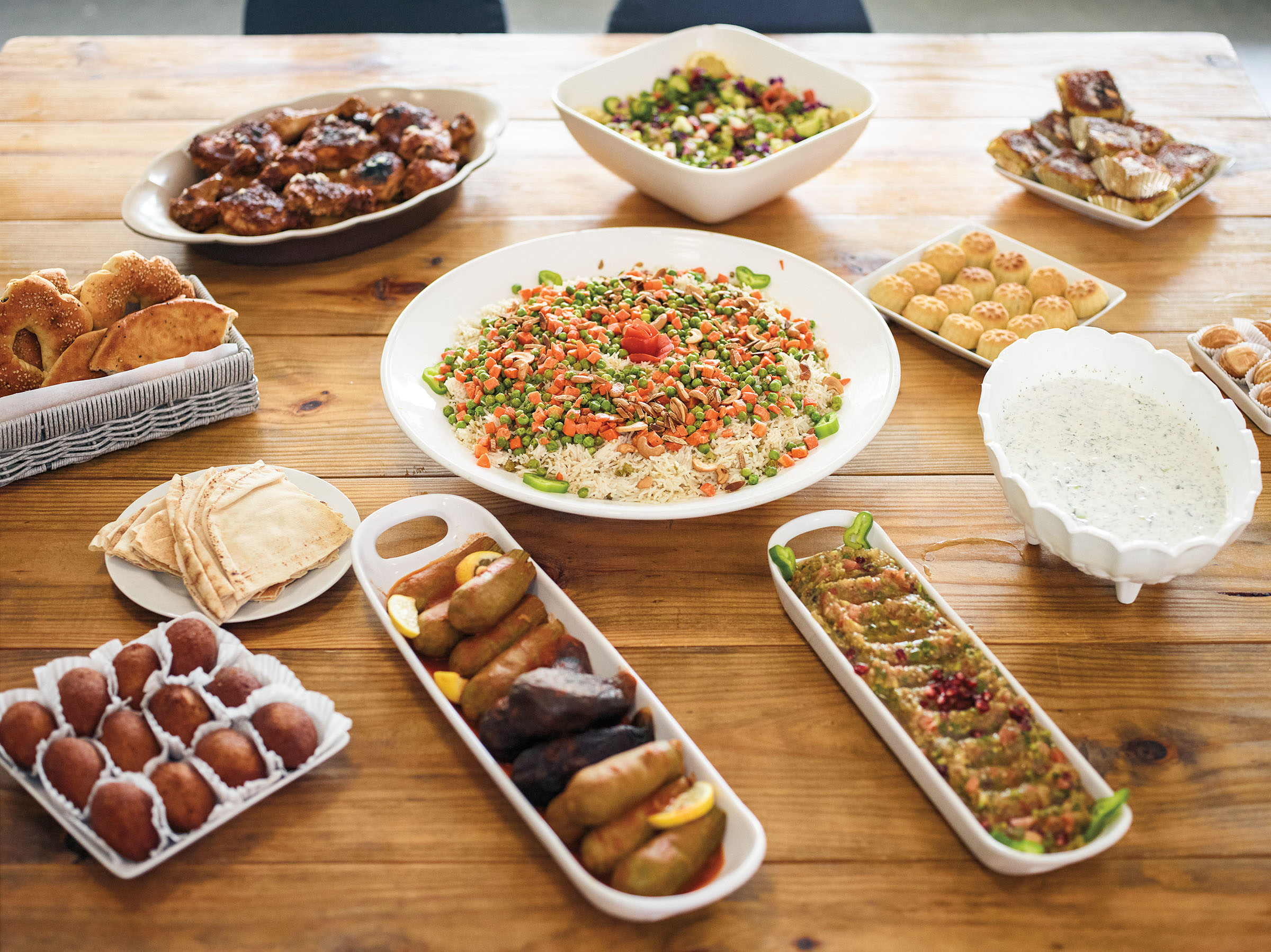 A collection of traditional Syrian dishes on platters on a wooden table