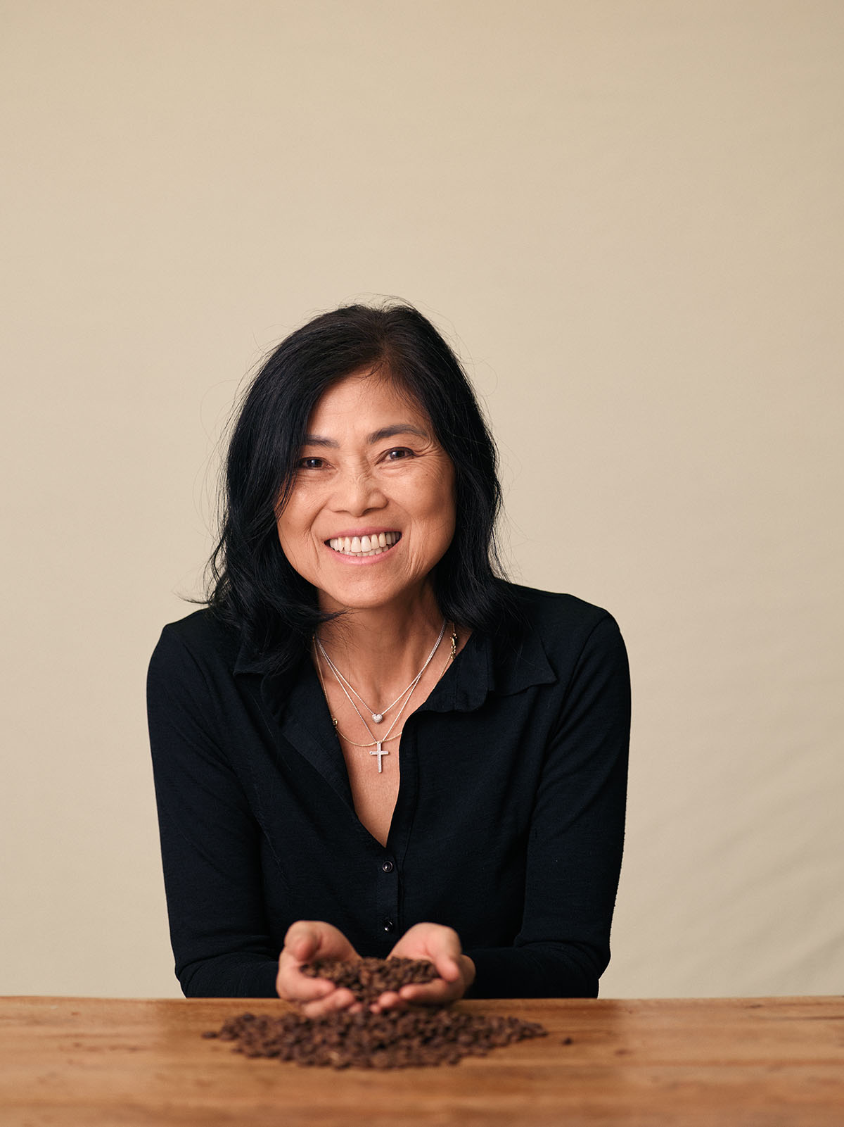 A woman in a black shirt with short black hair smiles in front of the camera