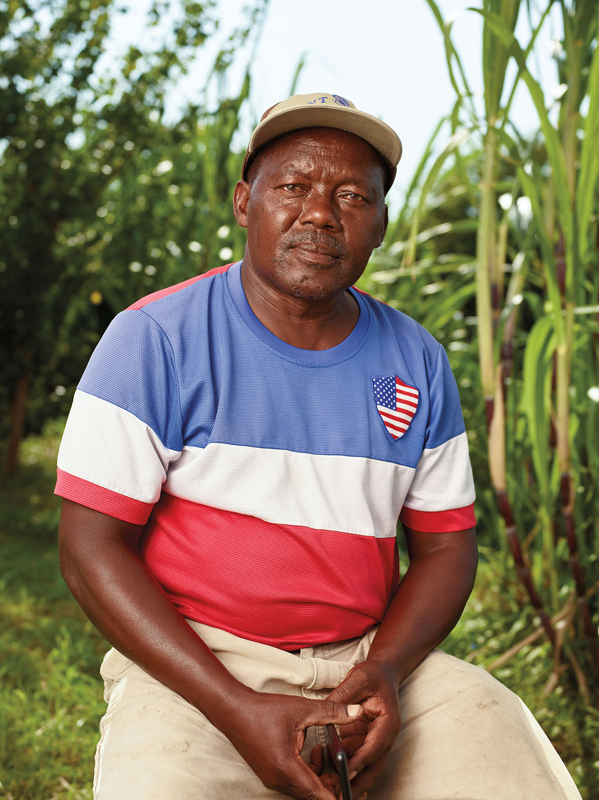 A man in a blue, white and red striped shirt and baseball cap poses for the camera