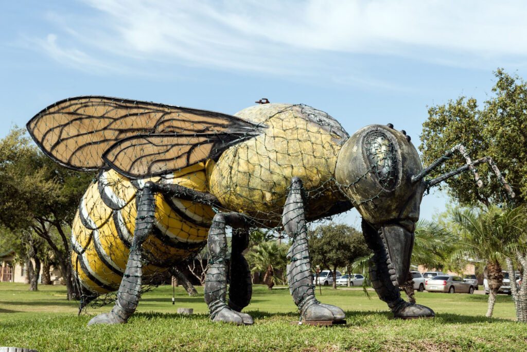 A large statue of a killer bee surrounded by grass