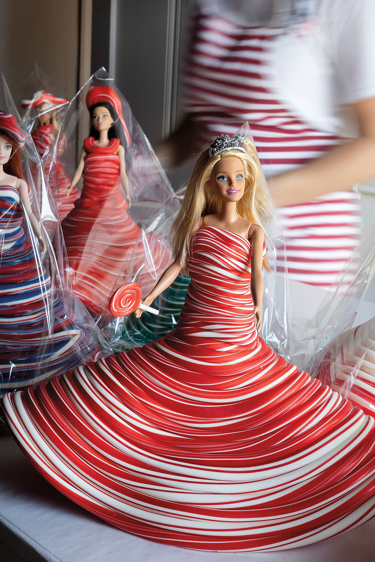 A Barbie doll with blonde hair wrapped in a red and white candy dress