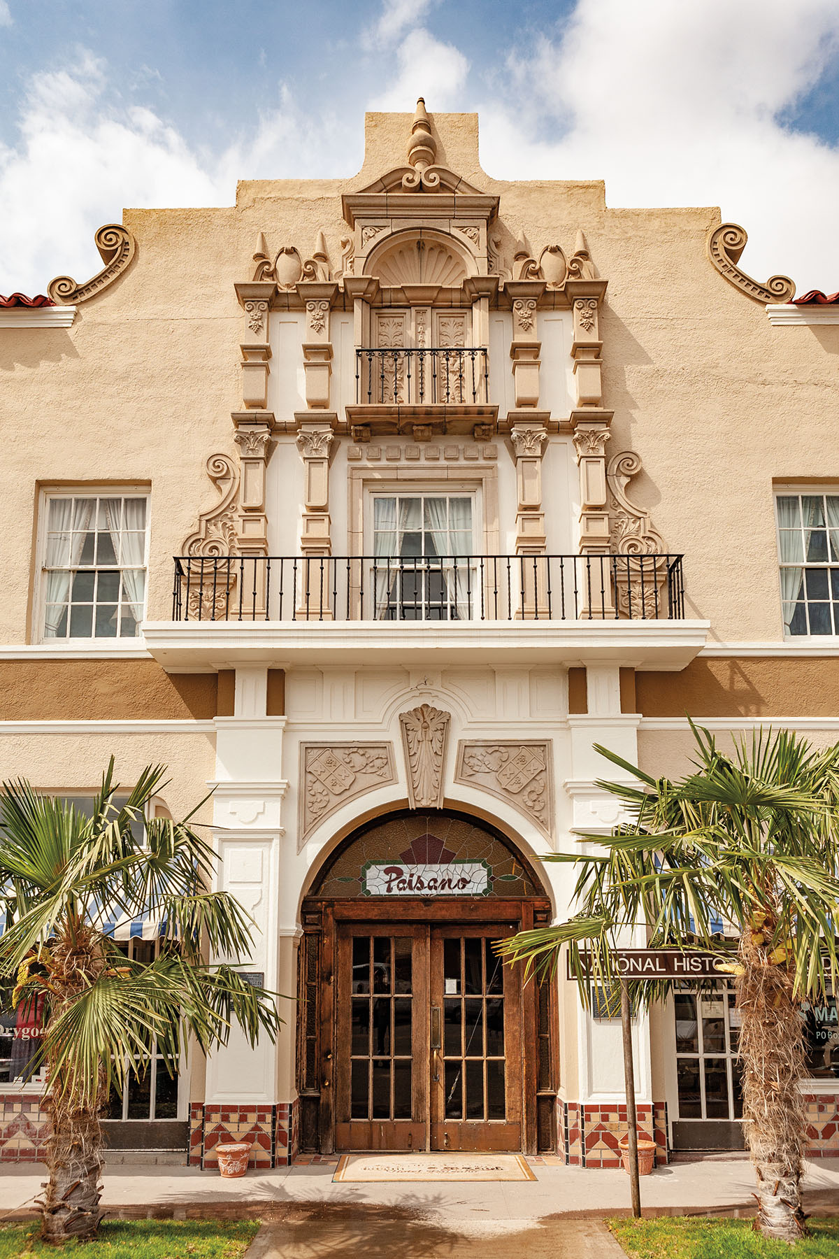 The dustry brown facade of an old hotel with a script sign reading "Pasiano"