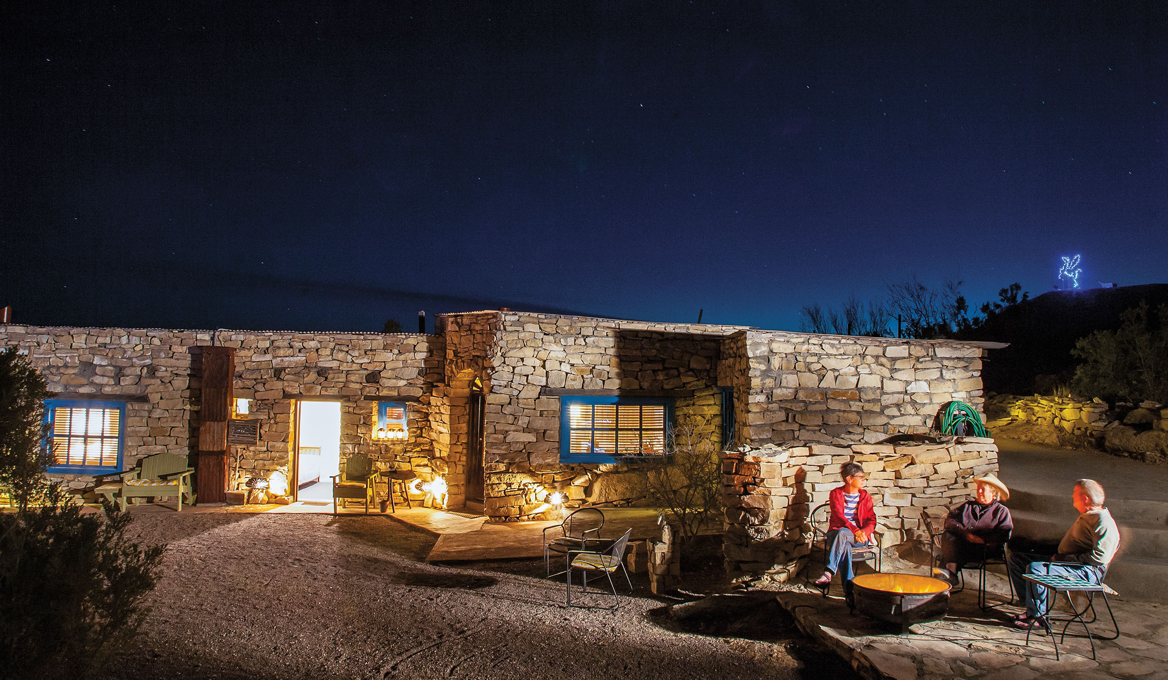 A nighttime photo of a stone hotel underneath a deep blue and black sky