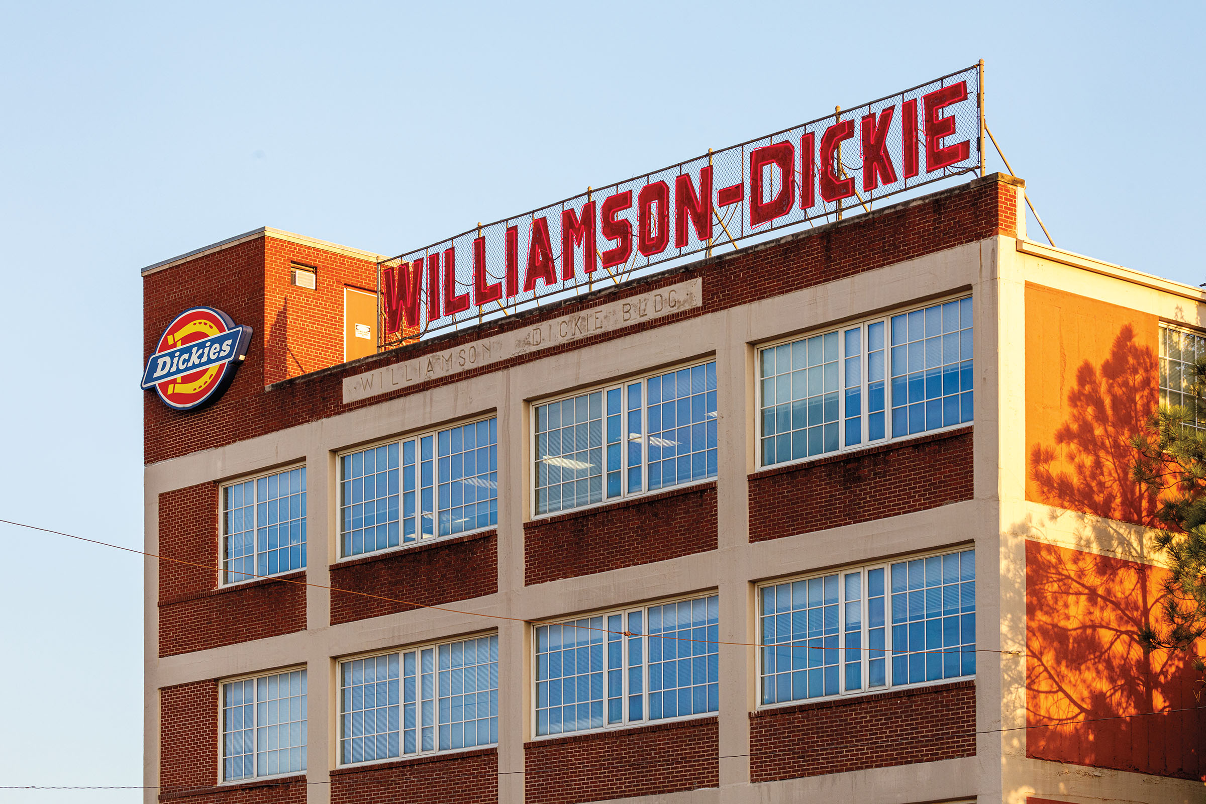 An outside view of a brick building in front of blue sky reading "Williamson-Dickie" on the outside