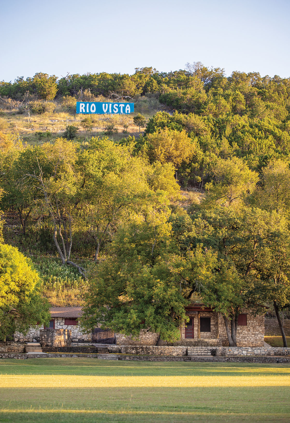 A tall, lush green hill with a blue sign reading "Rio Vista" above green grass below