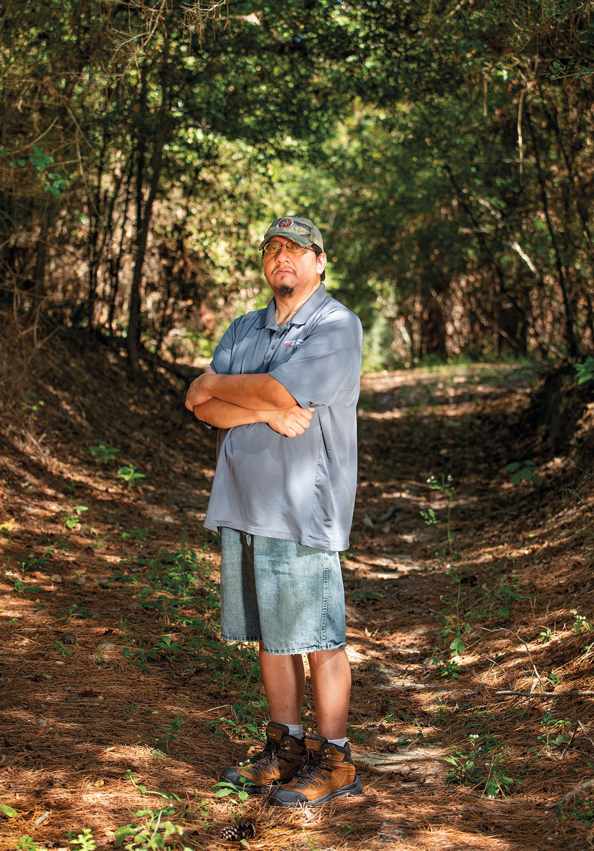 A man in a blue shirt stands with his arms crossed