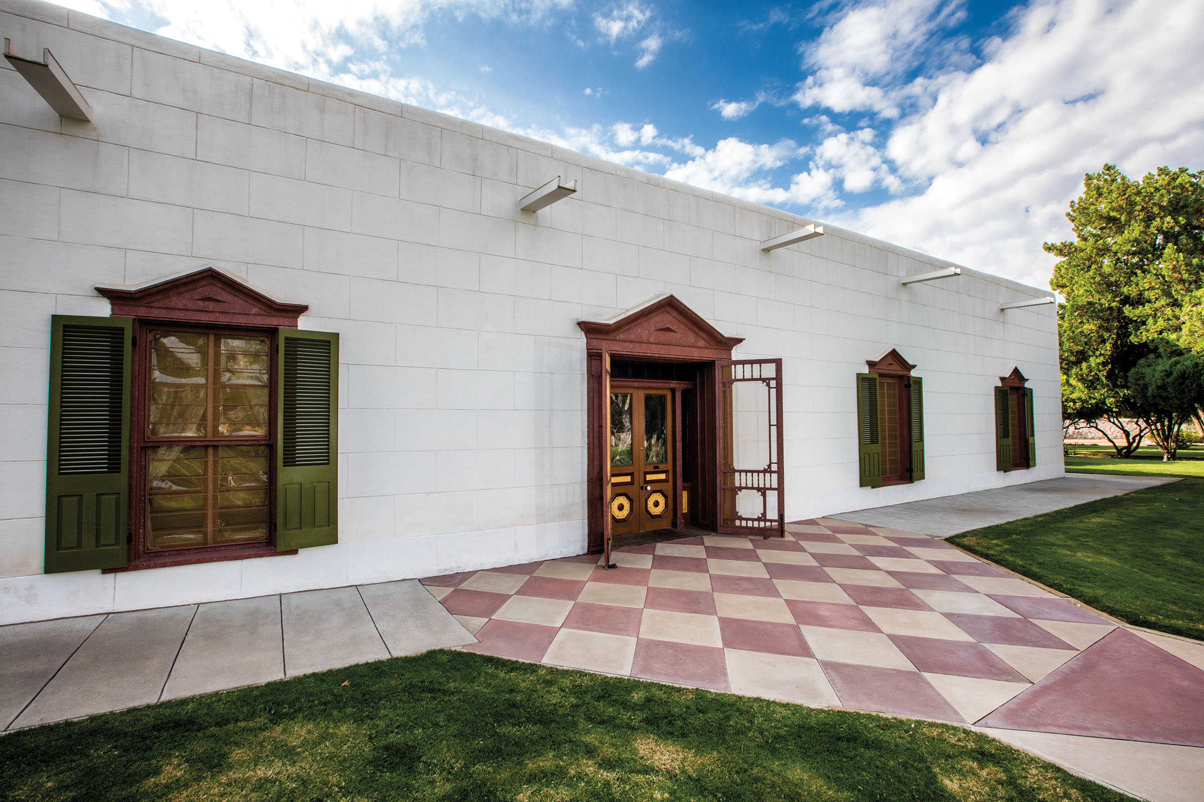 The outside of a white adobe building with a red and white checkered walkway