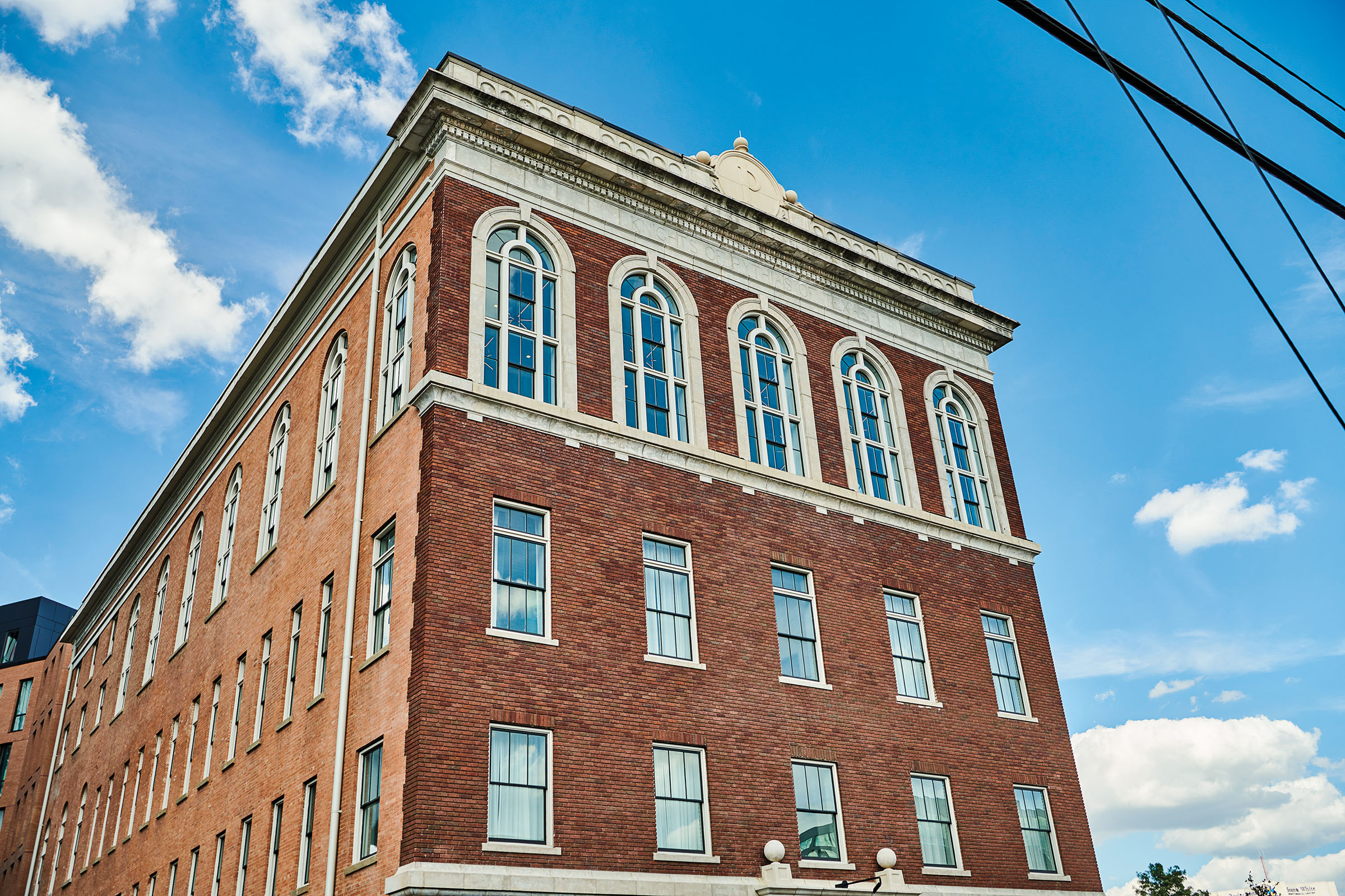 The outside of a brick building undearneath a black power line and blue sky