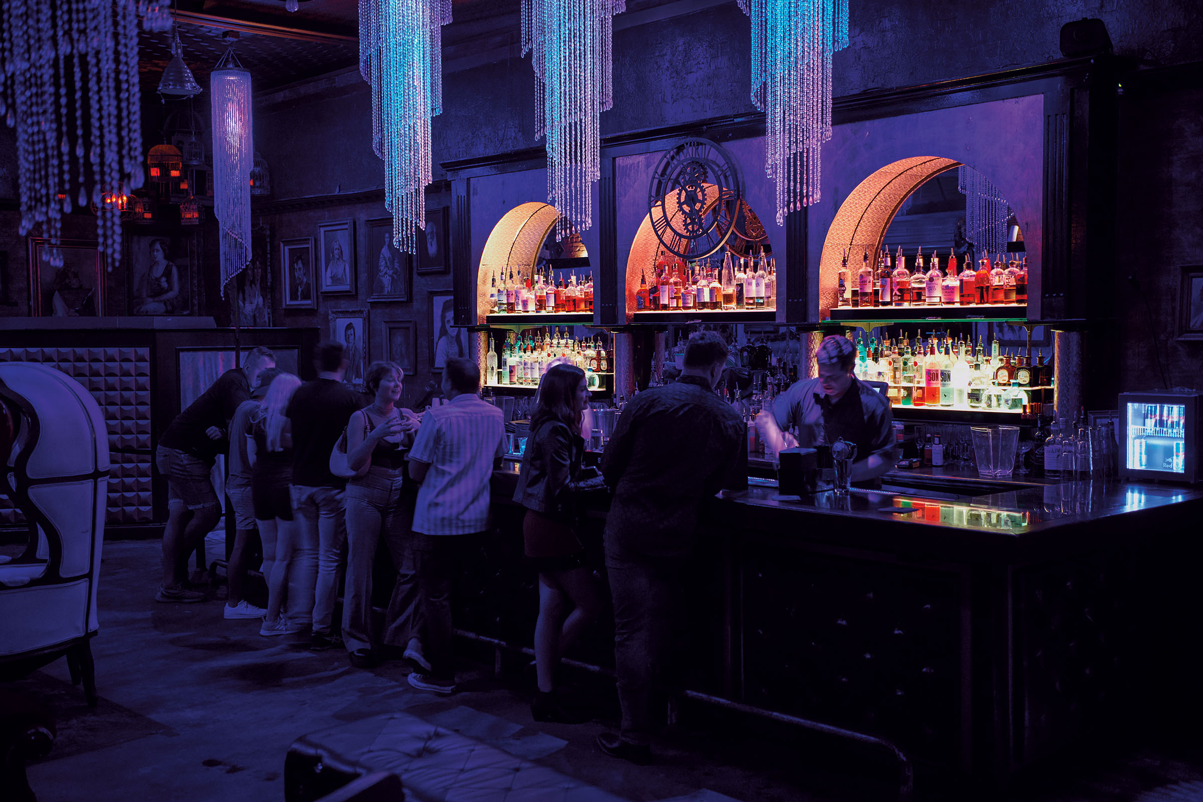 Orange, purple and blue tones in a muted, dark nightclub with chandeliers hanging from the ceiling