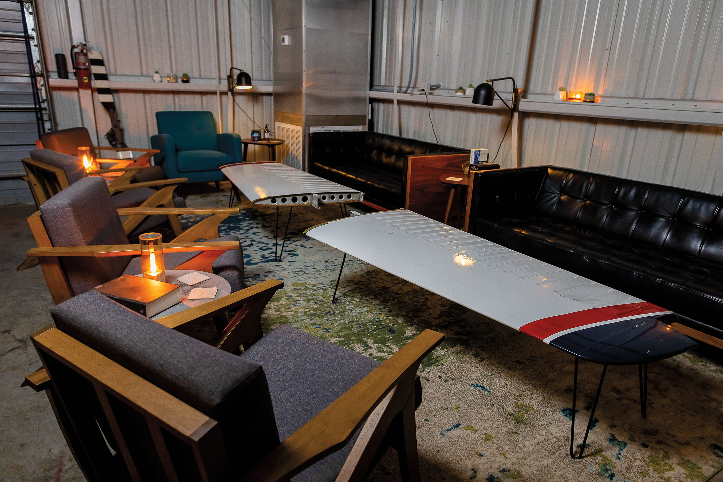 A plushly-decorated seating area with tables made from airplane wings and modern couches and chairs