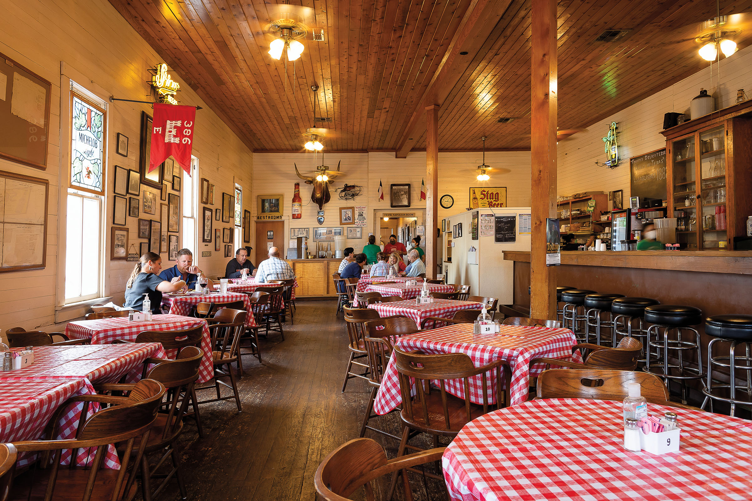 A well-lit wooden interior of a restaurant with several checker-covered tables