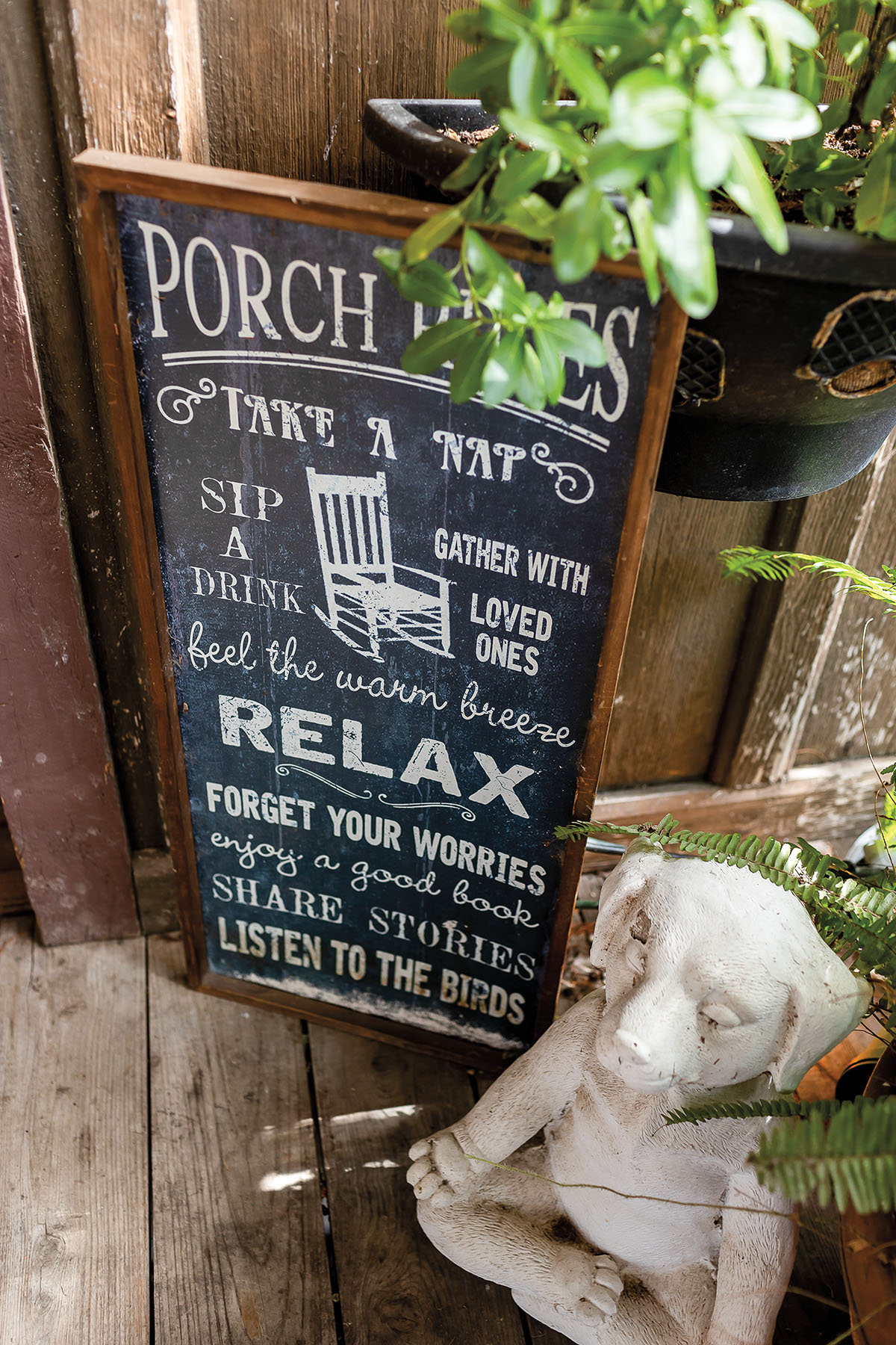 A chalk sign reading relaxing statements like "Take a nap, sip a drink, gather with loved ones, feel the warm breeze, relax, forget your worries, enjoy a good book, share stories, listen to the birds"