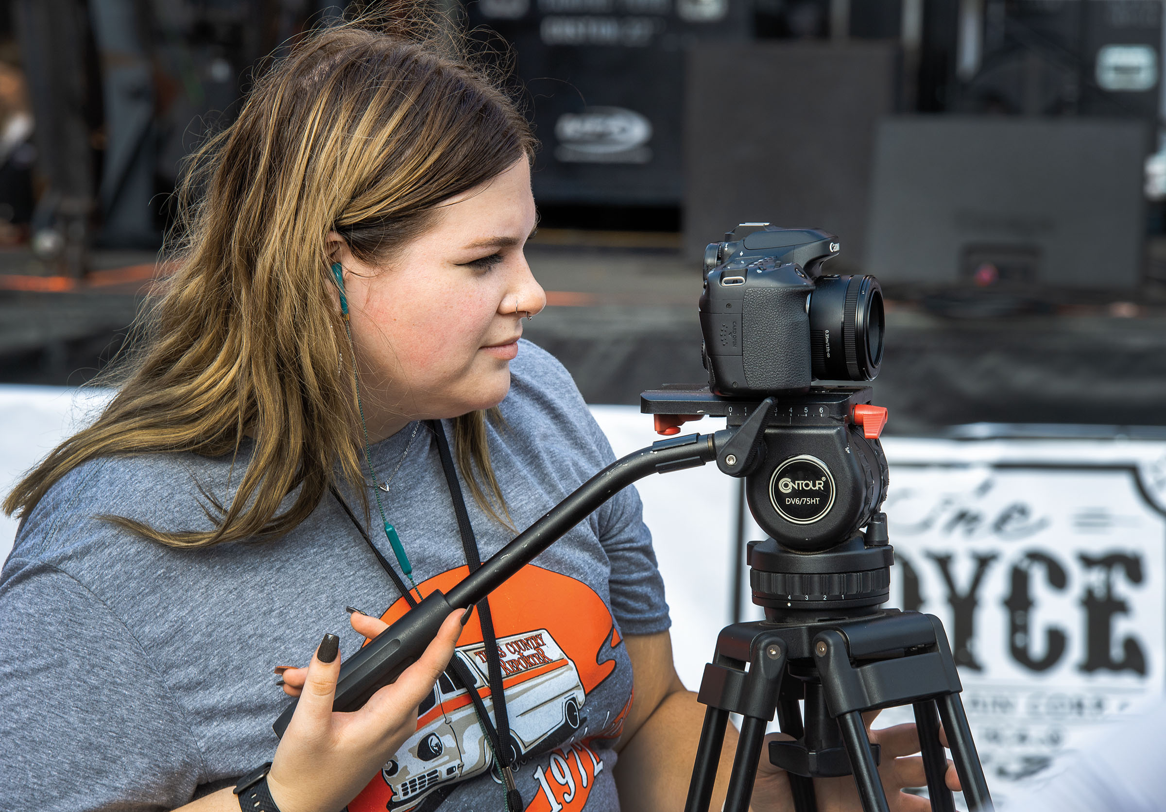 A woman holds a tripod with a camera attached