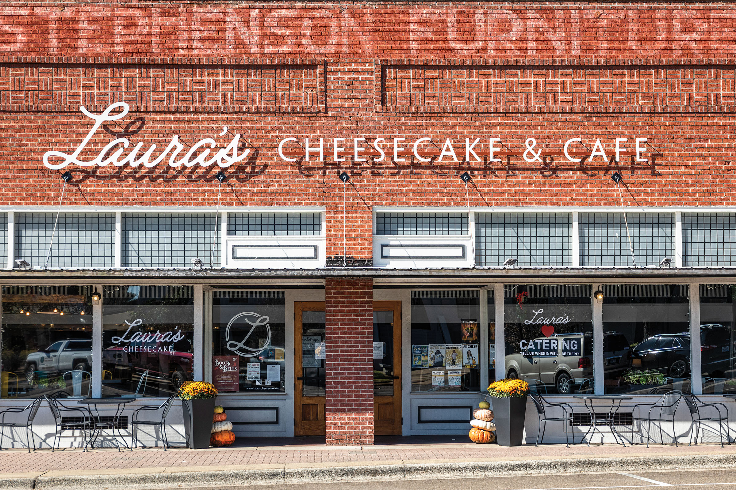 The exterior of a brick and glass block building reading "Laura's Cheesecake & Cafe"