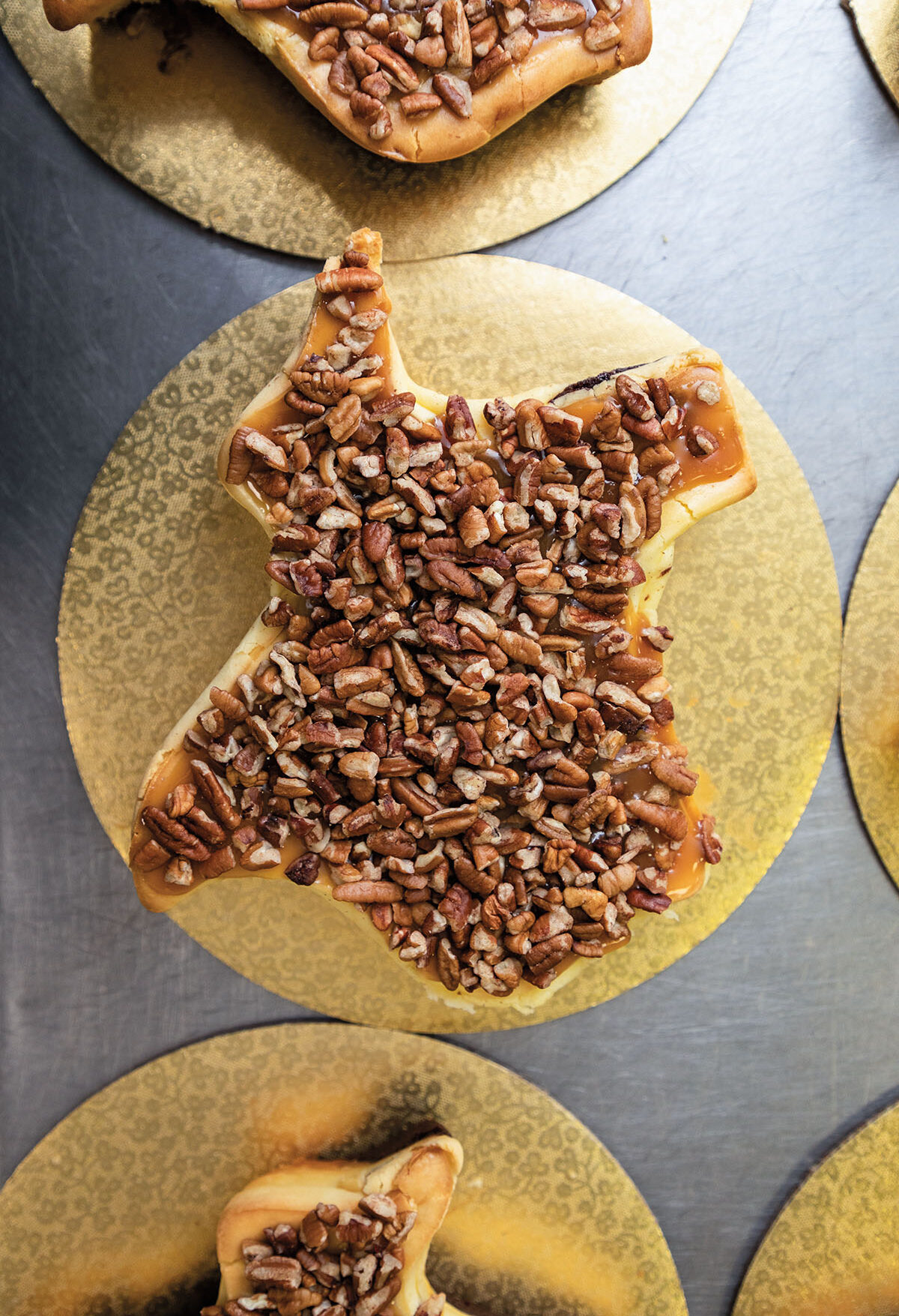 An overhead view of Texas-shaped cheesecakes topped with pecans on a gold platter