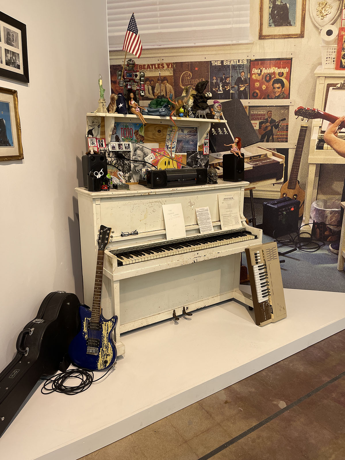 A piano, guitars, and other decorations in a museum exhibit