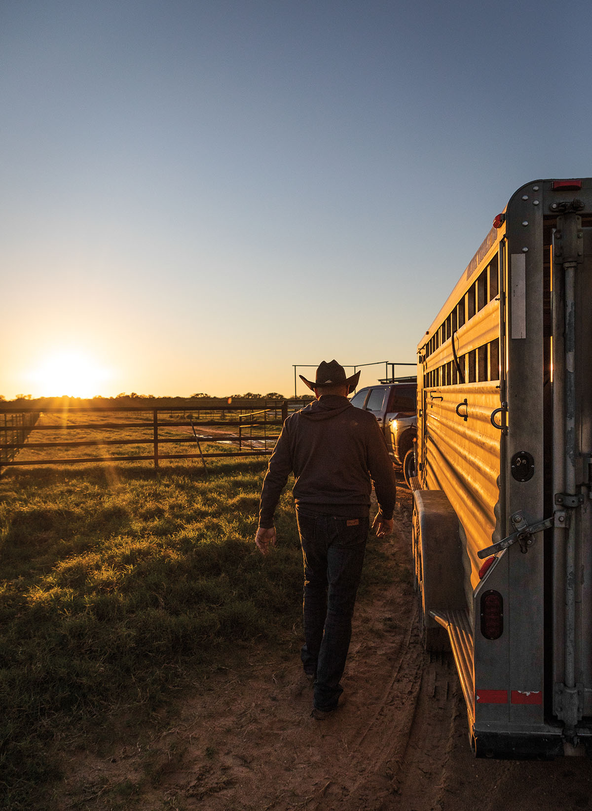 A man in a cowboy hat walks past a trailer