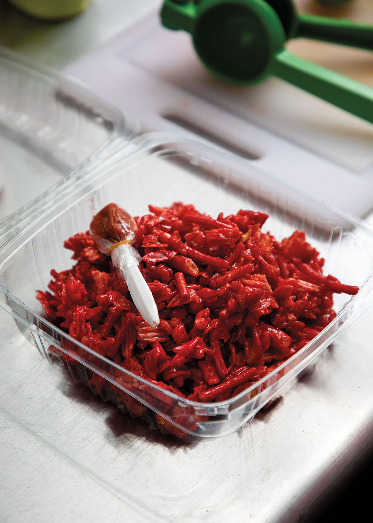 A container of bright red candies with a small bag of spicy seasoning