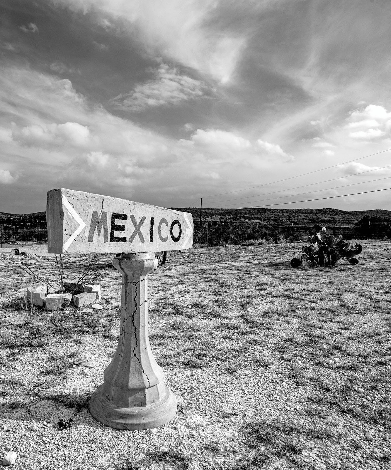 A black and white sign reading 'MEXICO' on a desert landscape