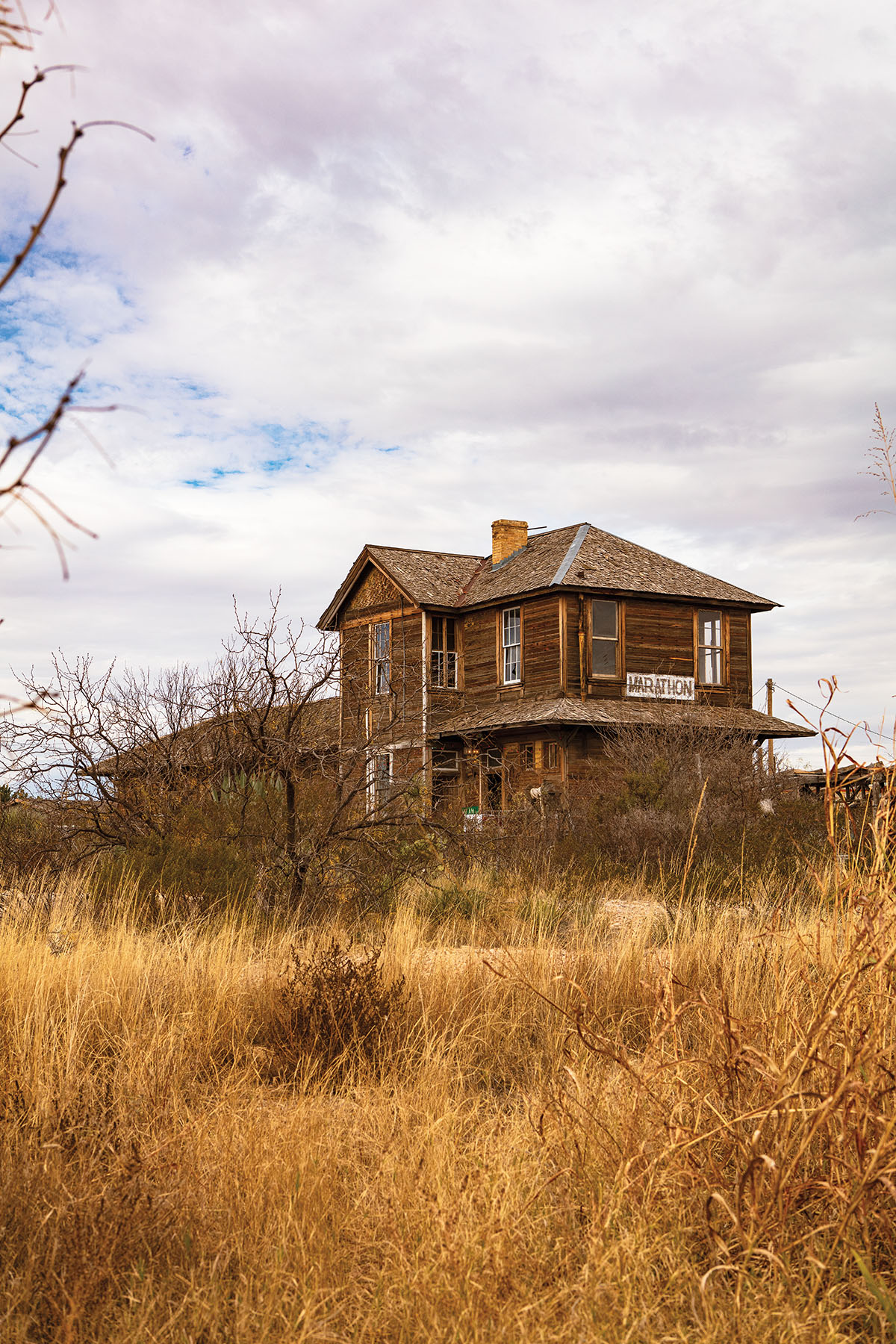 A wooden house in a golden field under blue sky