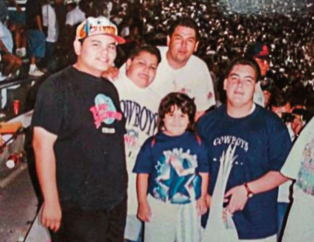 A group of men in t-shirts pose in an old family photograph