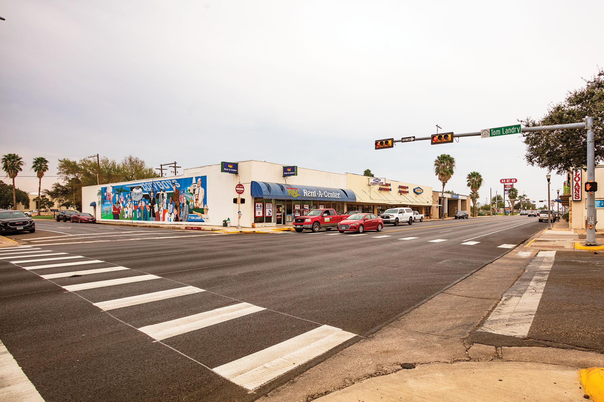 A street scene with a crosswalk and mural painted on the side of a white building