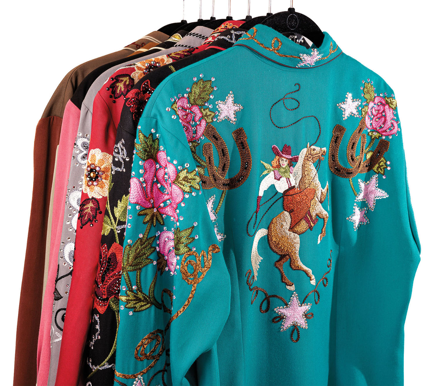 A rack of brightly colored clothing featuring intricate designs of wildflowers, cowgirls and cacti