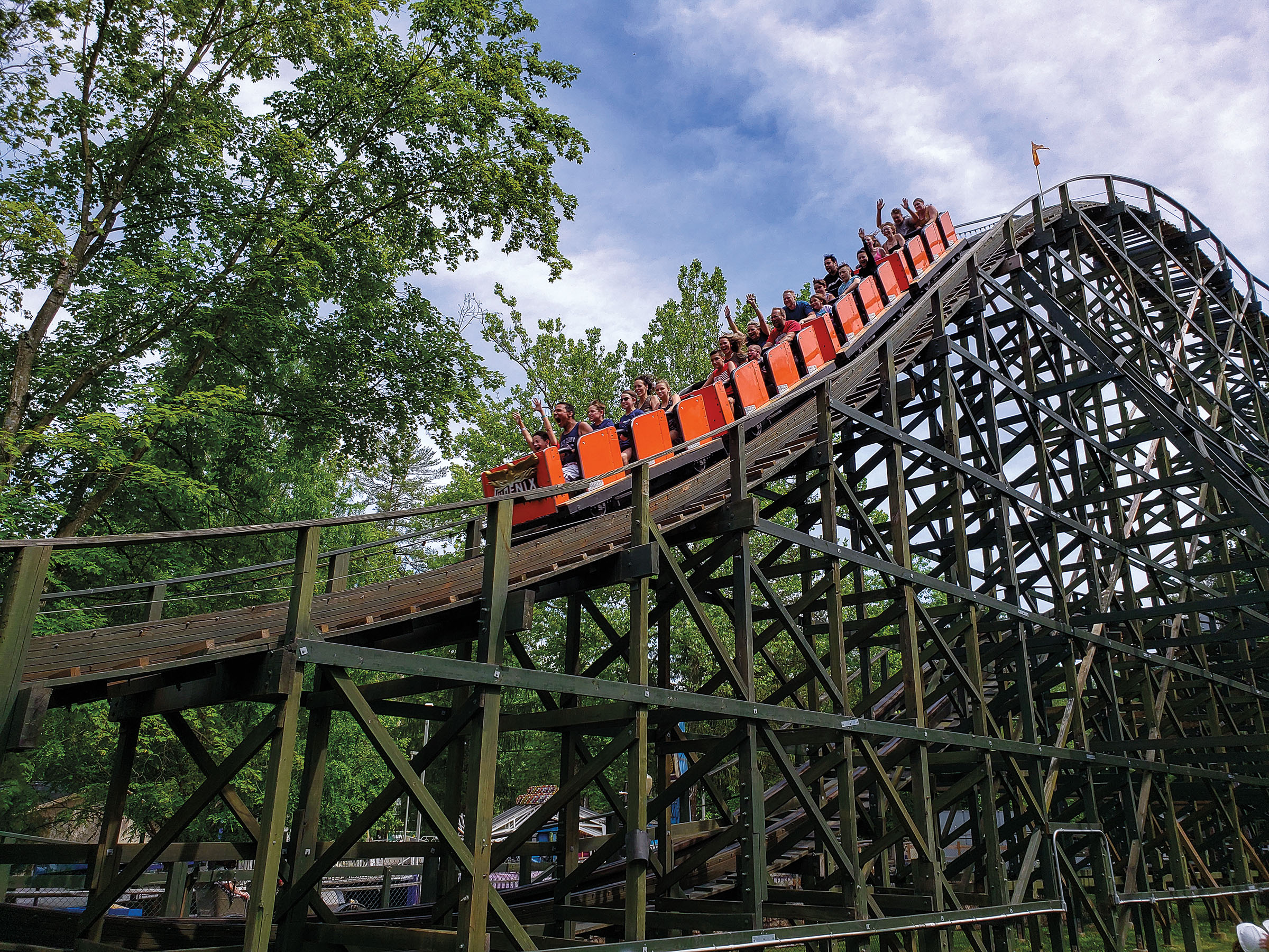 An image of a red roller coaster on a wooden track under a blue sky