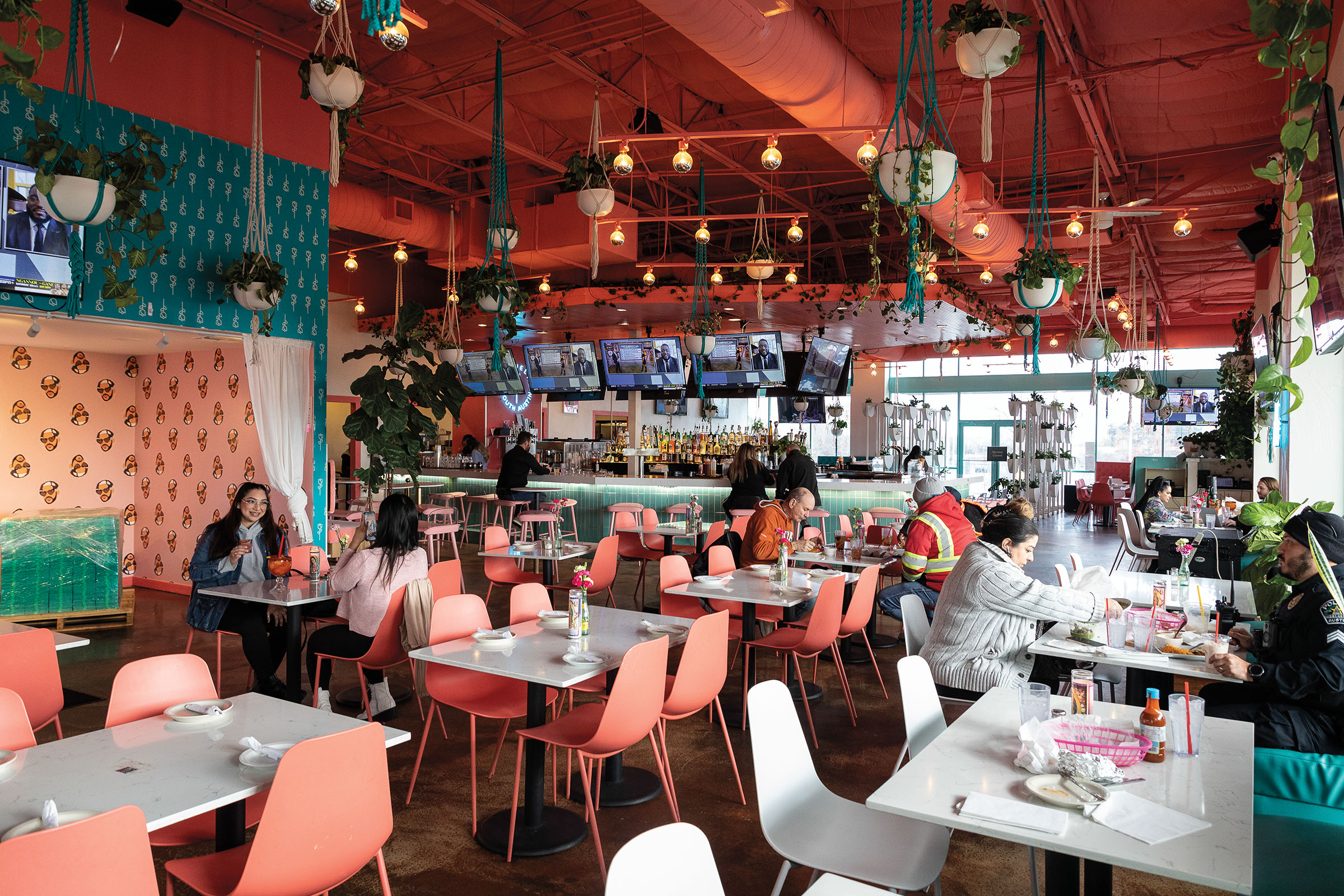 A picture of a brightly-colored and whimsically-decorated restaurant, including disco balls, pink paint, pink and white chairs, and bright white tables