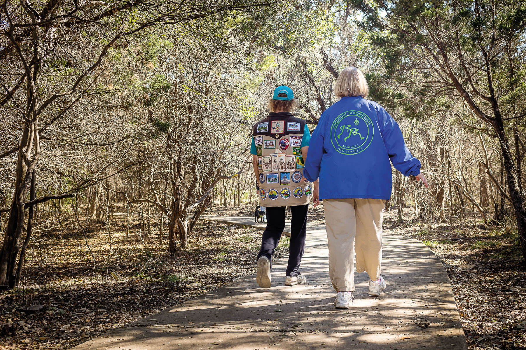 An image of two people walking together through a wooded area