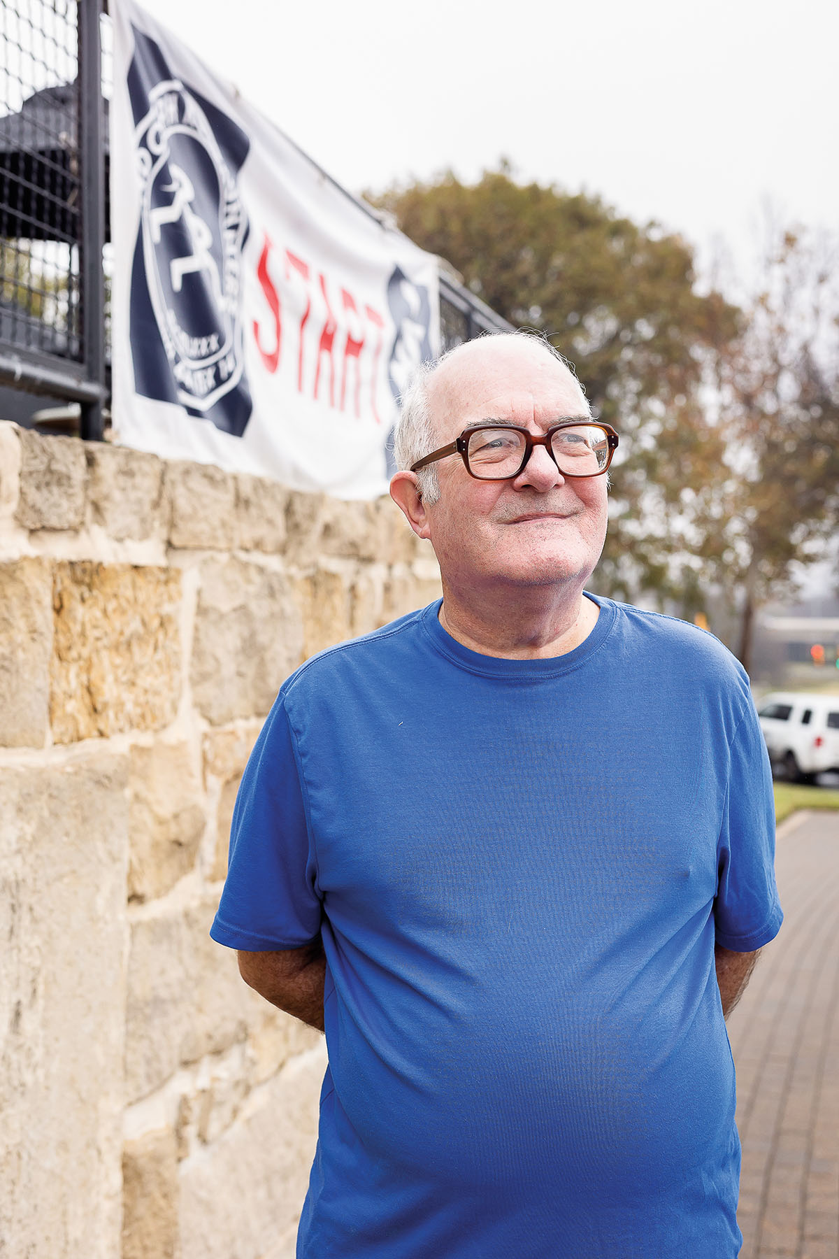 A picture of a man in a blue shirt and glasses smiling