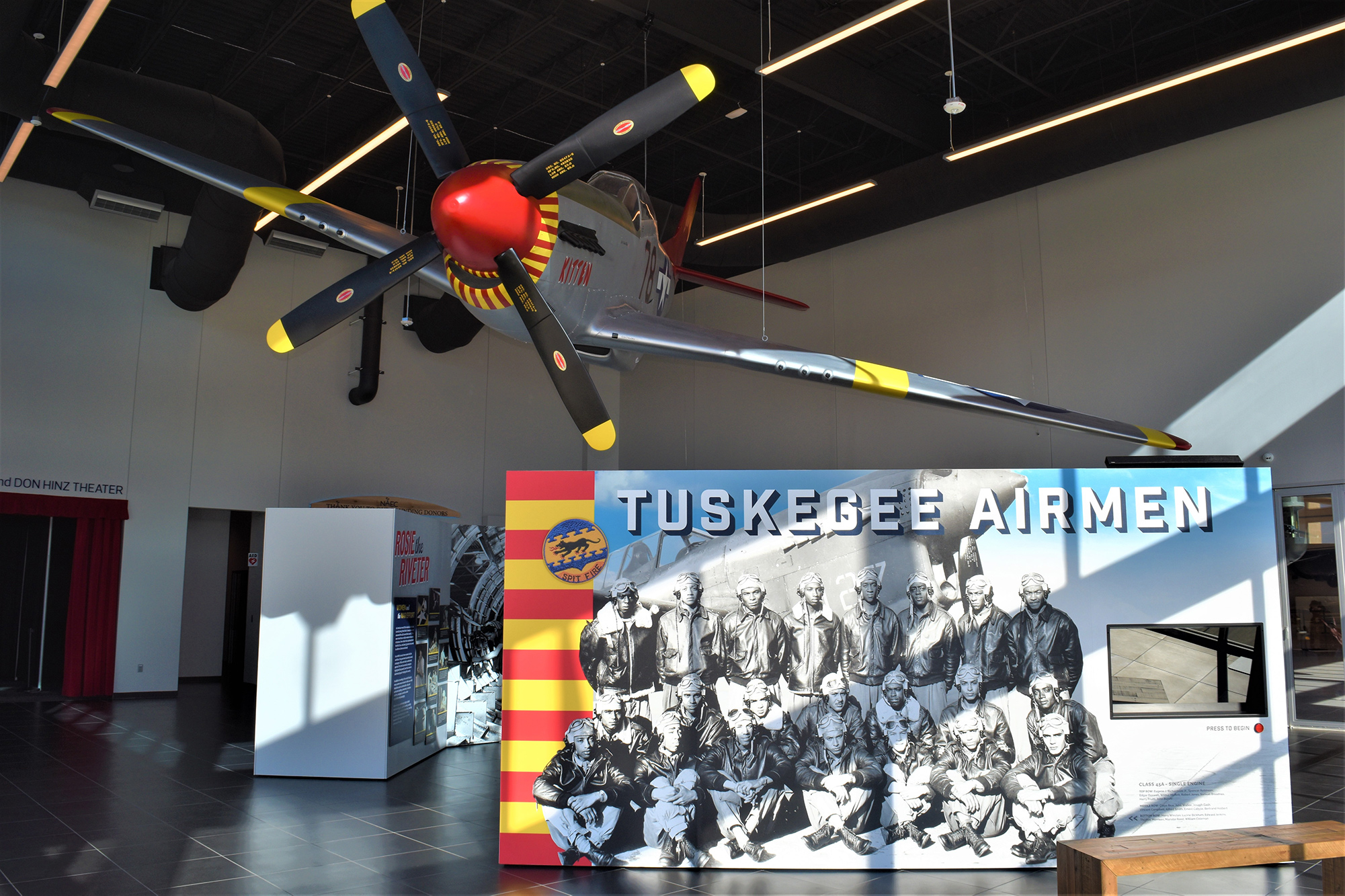 A display at the Commemorate Air Force museum about the Tuskegee Airmen, with an aircraft hanging from the ceiling and a large photo display on the right