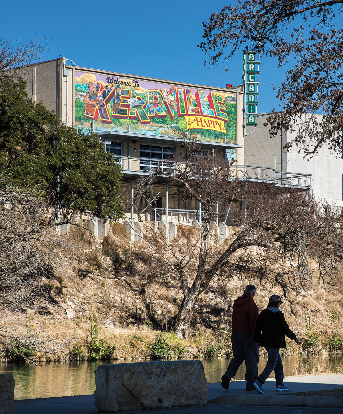 A mural reading "Kerrville" above a small hill where two people are walking