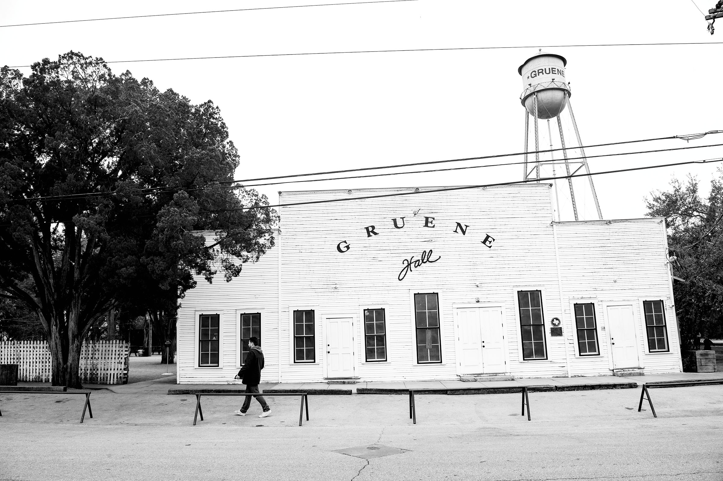 A black and white photo of the outside of a building reading "Gruene Hall" under a water tower