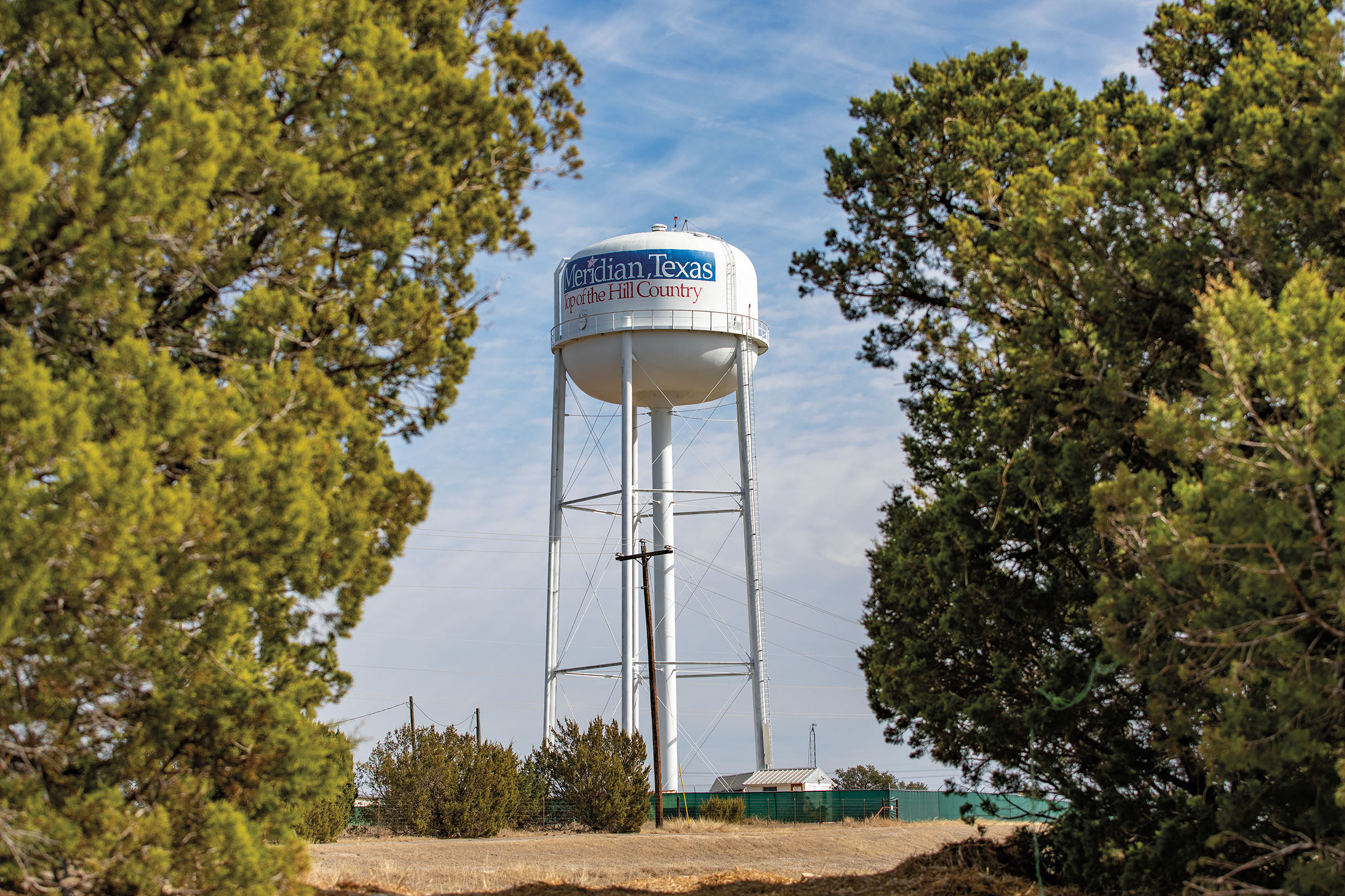 A tall white water tower reading "Meridian Texas: Top of the Hill Country"