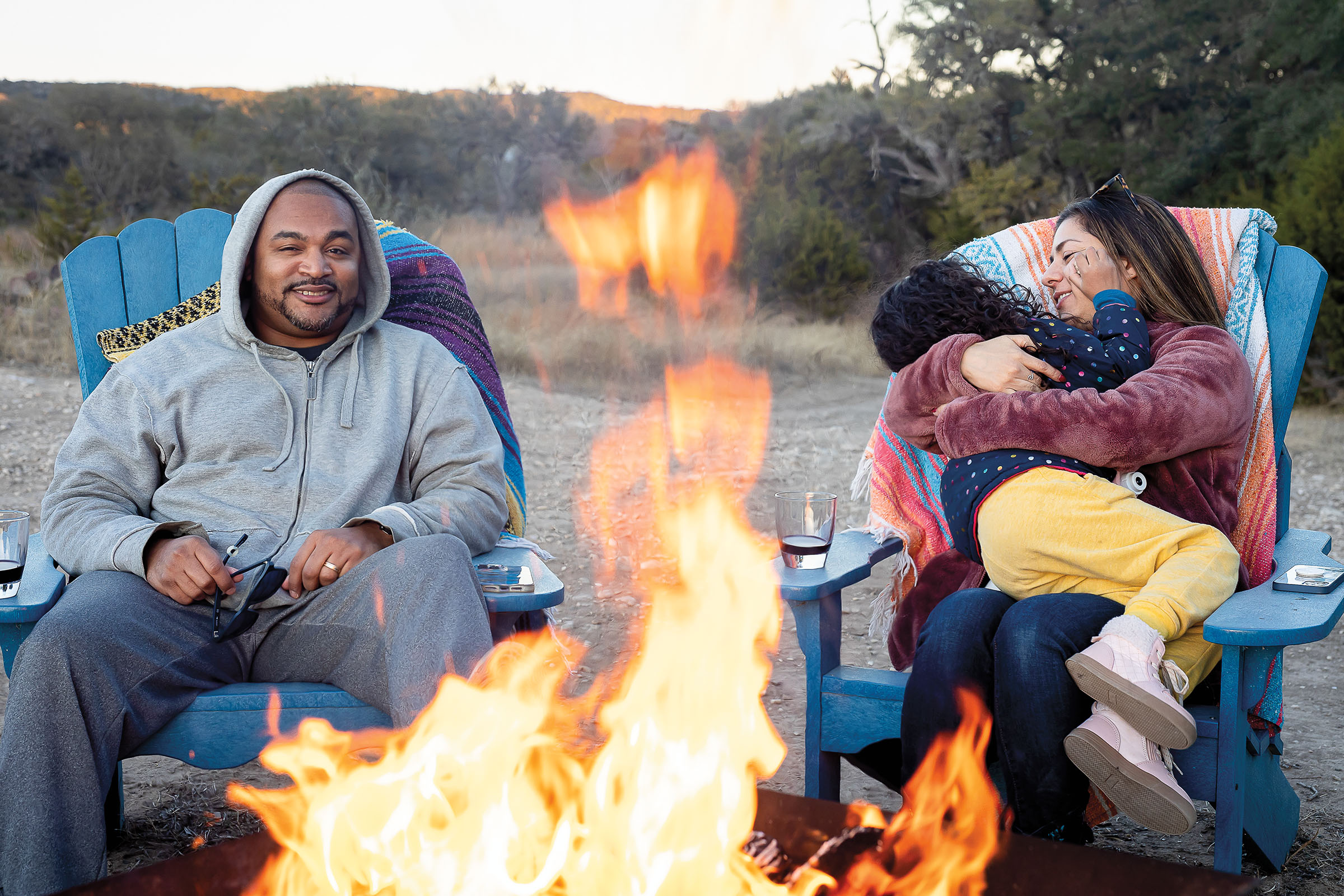 A family sits and embraces behind a roaring fire