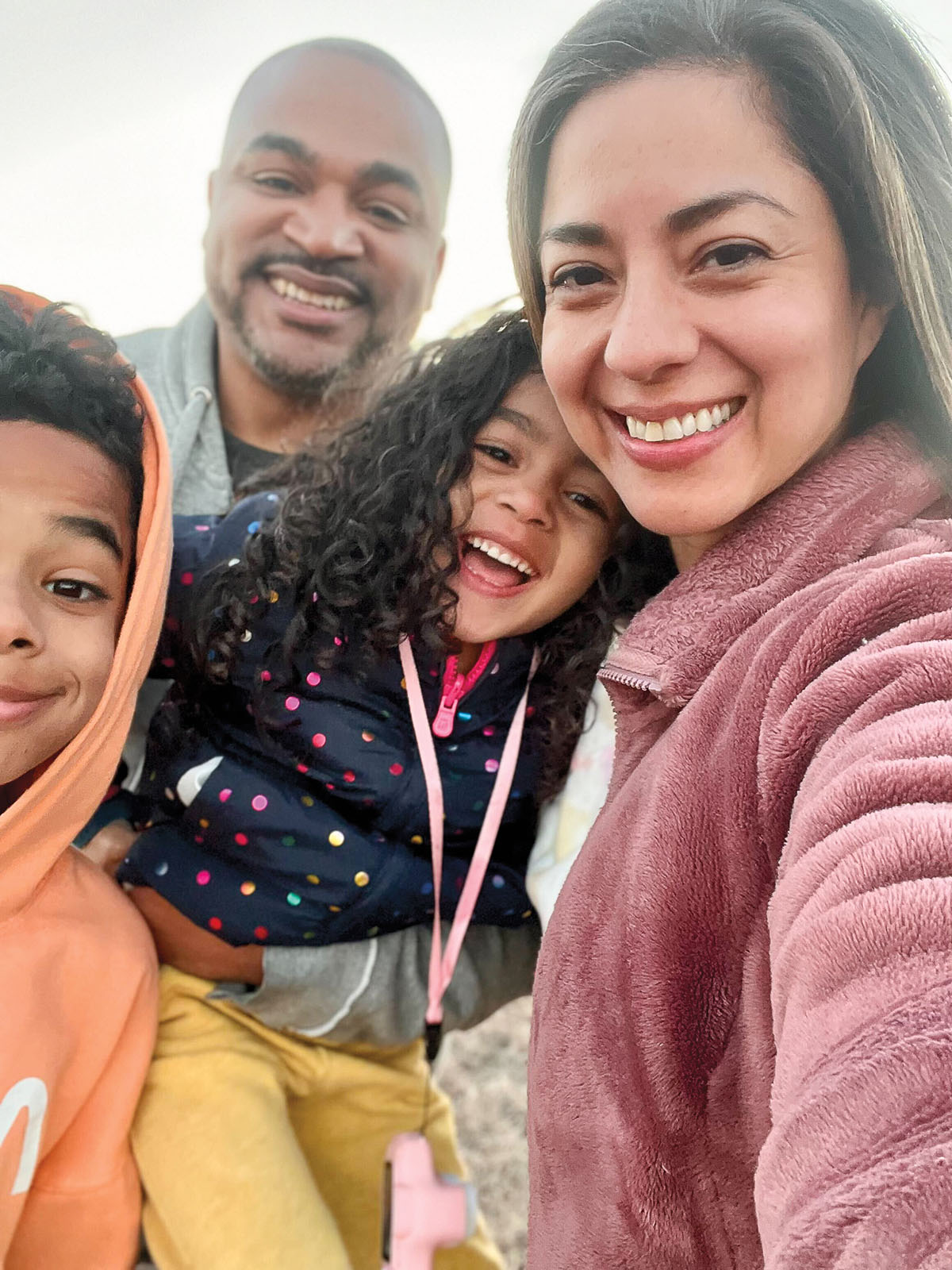 A group of four people in cool-weather attire pose for a selfie