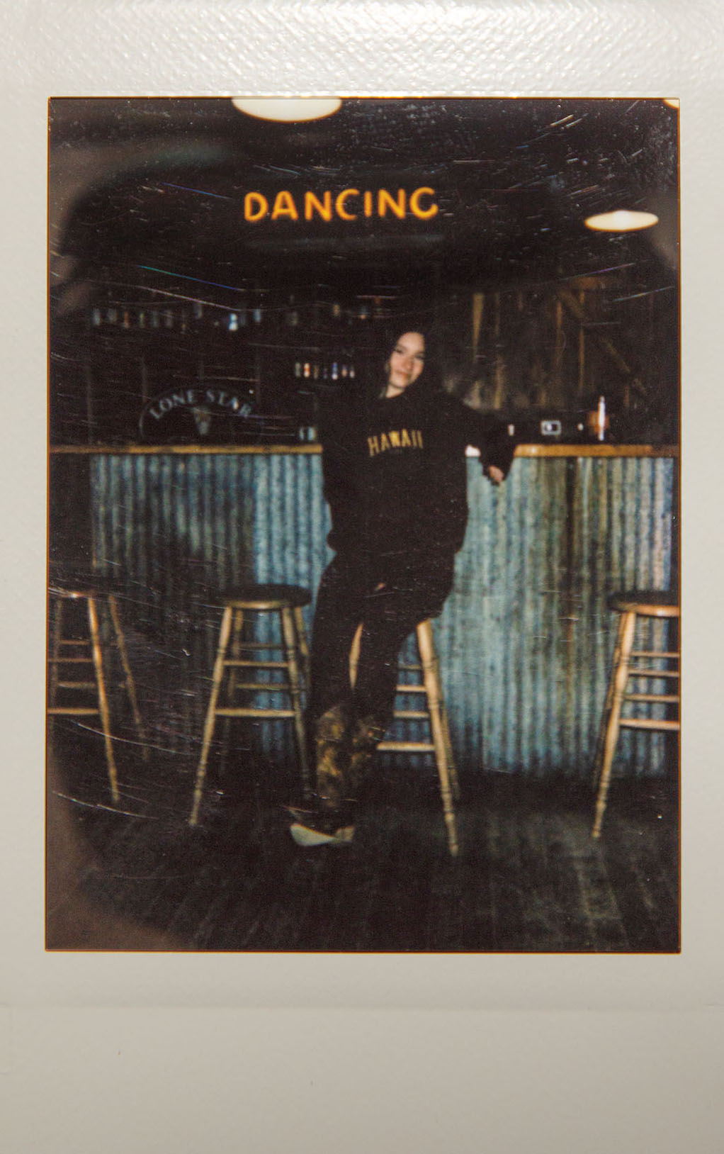 A woman shows off cowboy boots in front of a metal bar