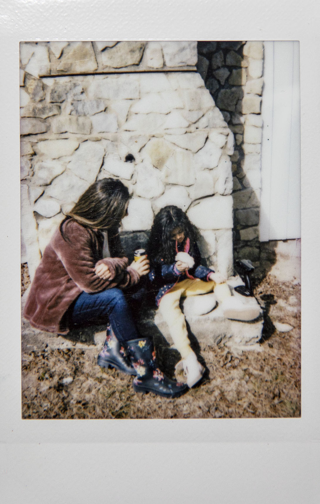 A Polaroid picture of two women looking at rocks in an outdoor setting
