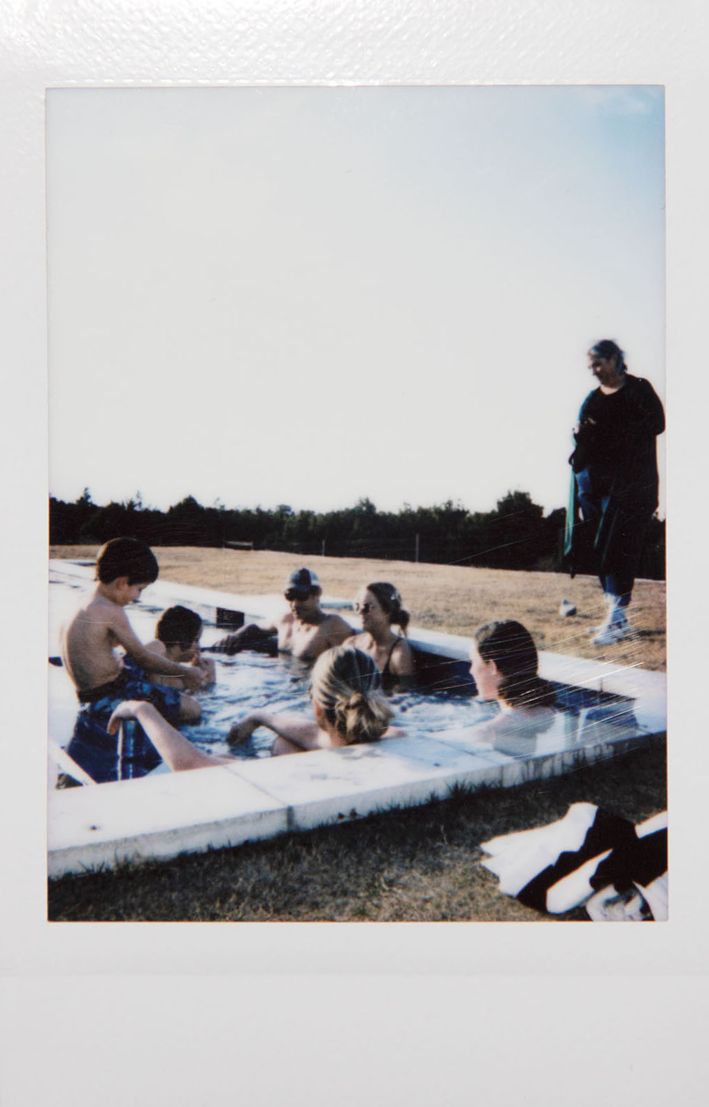 A Polaroid picture of people hanging out in a hot tub