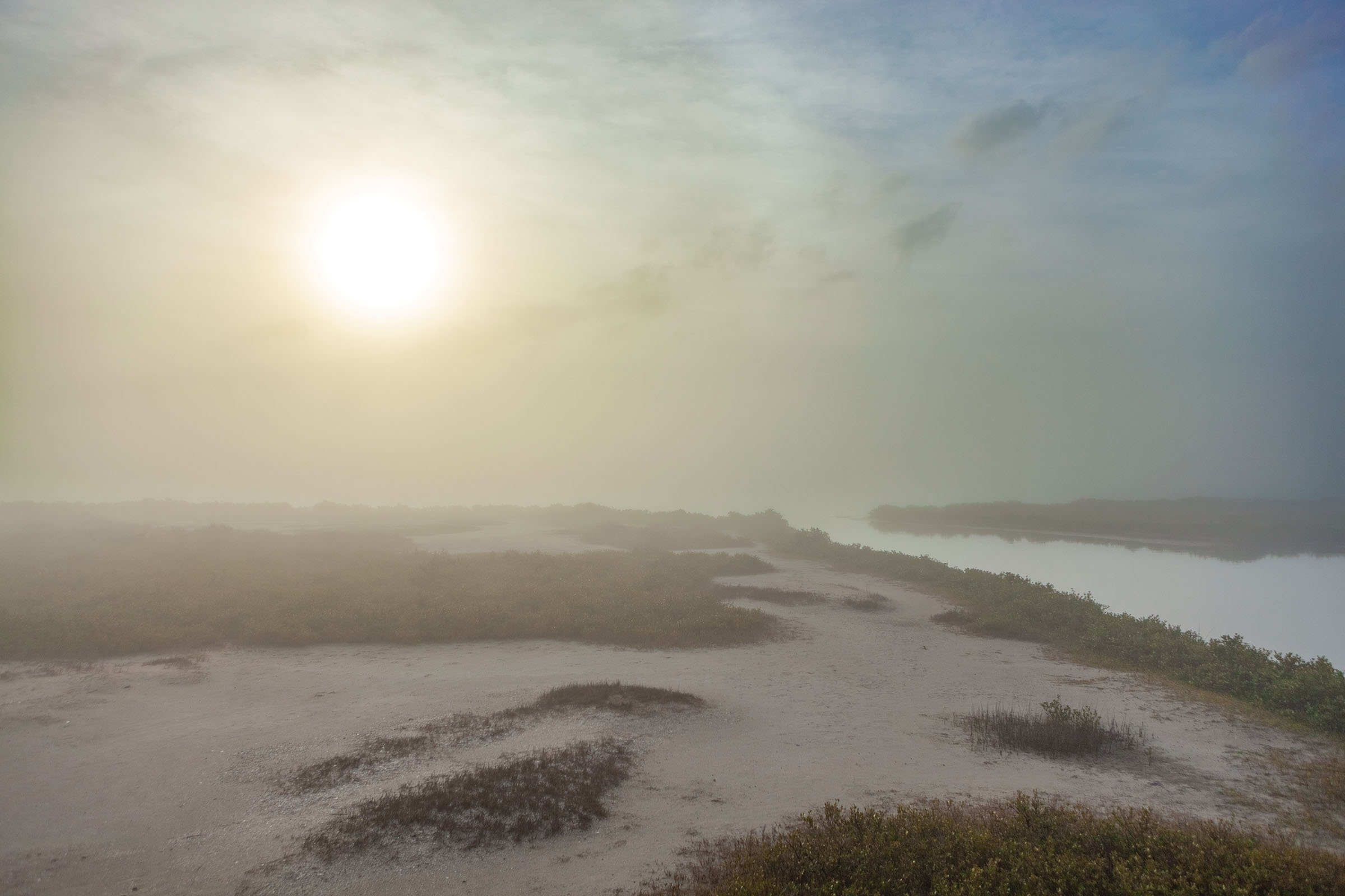 The sun shines brightly over a grassy, sandy island