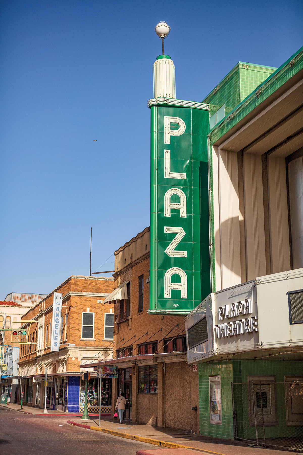 The outside of a brick theater with a large green sign reading 