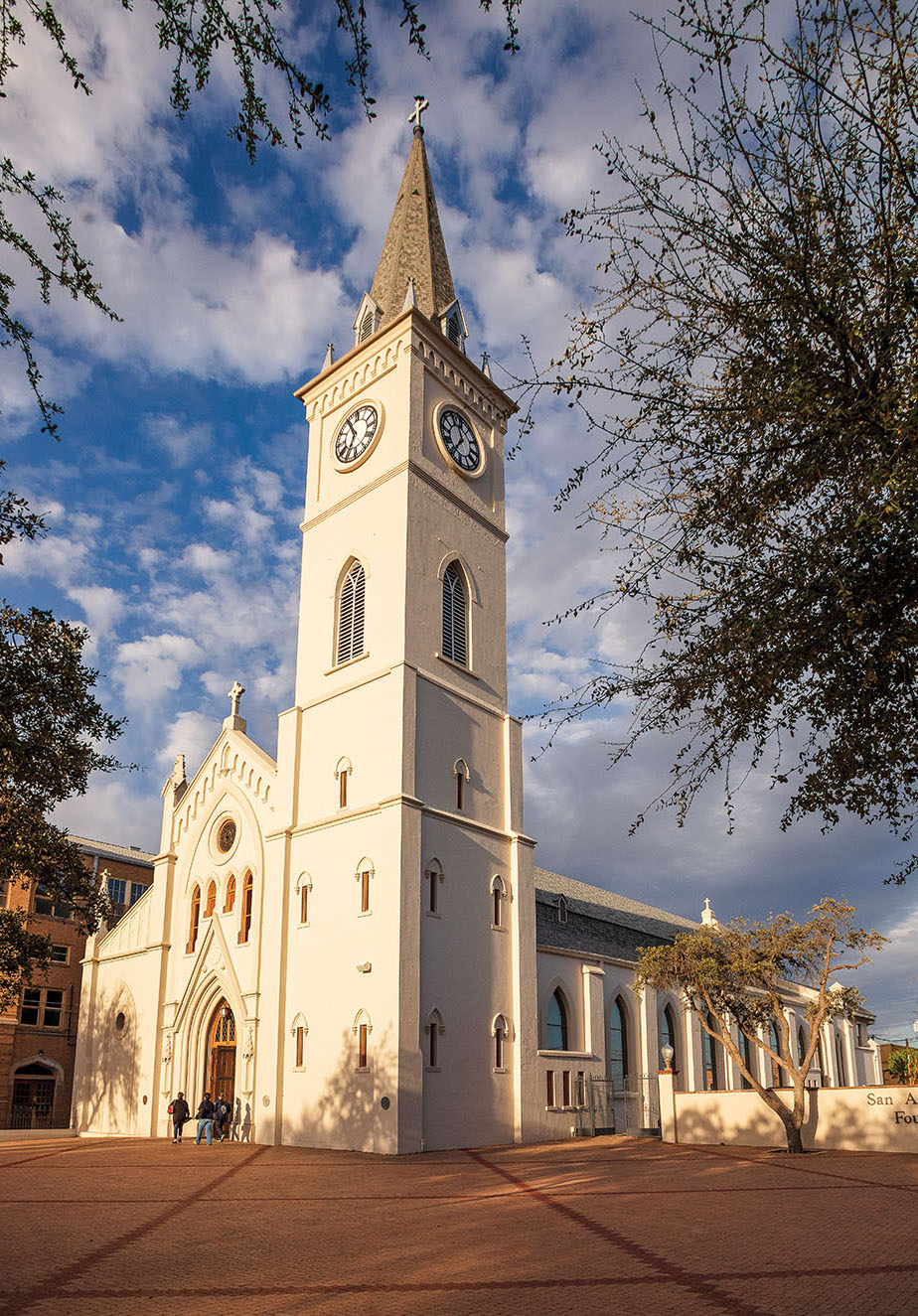 A tall, ivory-colored cathedral in front of a blue sky with a few clouds