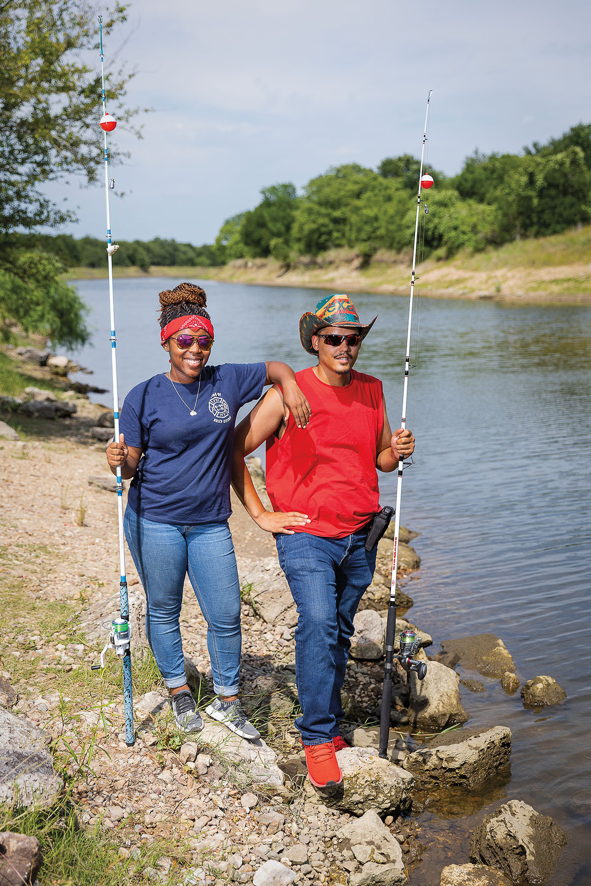 Two people stand holding fishing rods on the rocky banks of the Brazos river