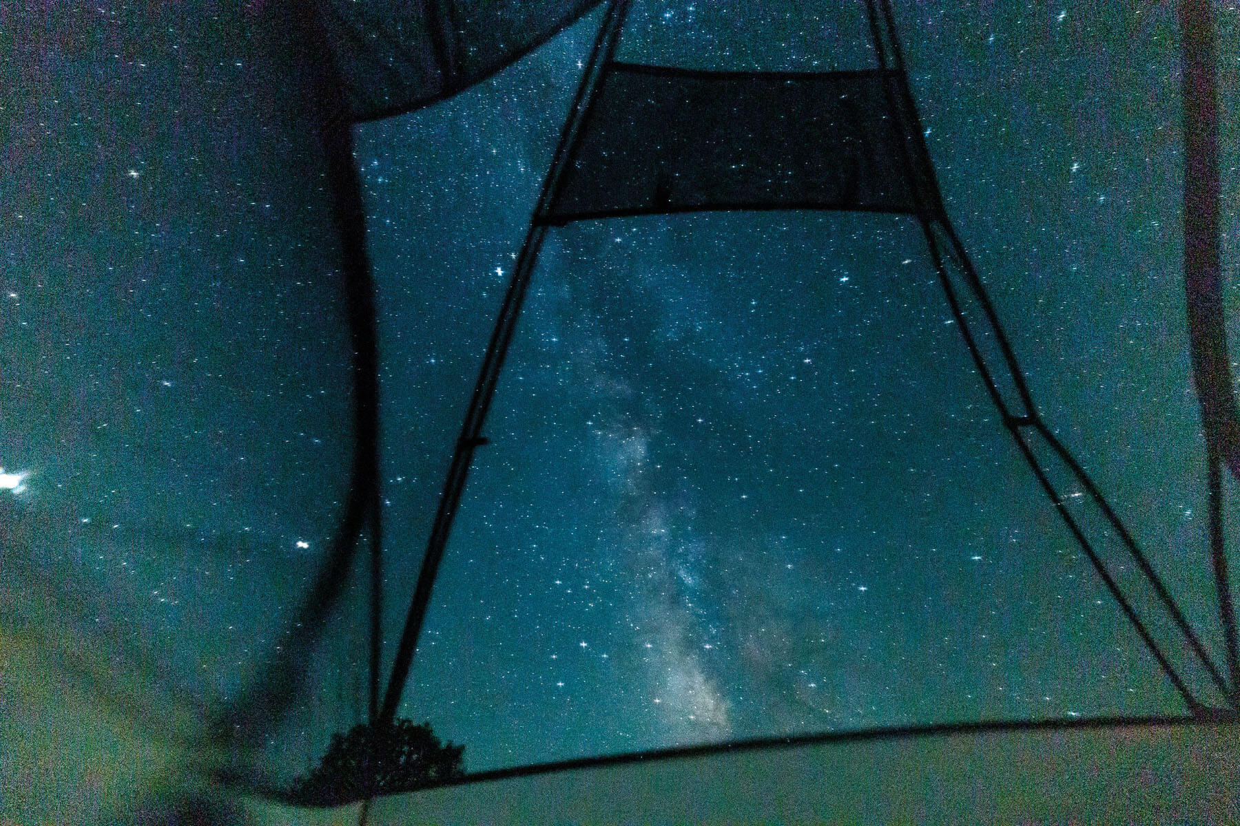 A dark bluish black sky with bright stars peeks through vents in the roof of a tent